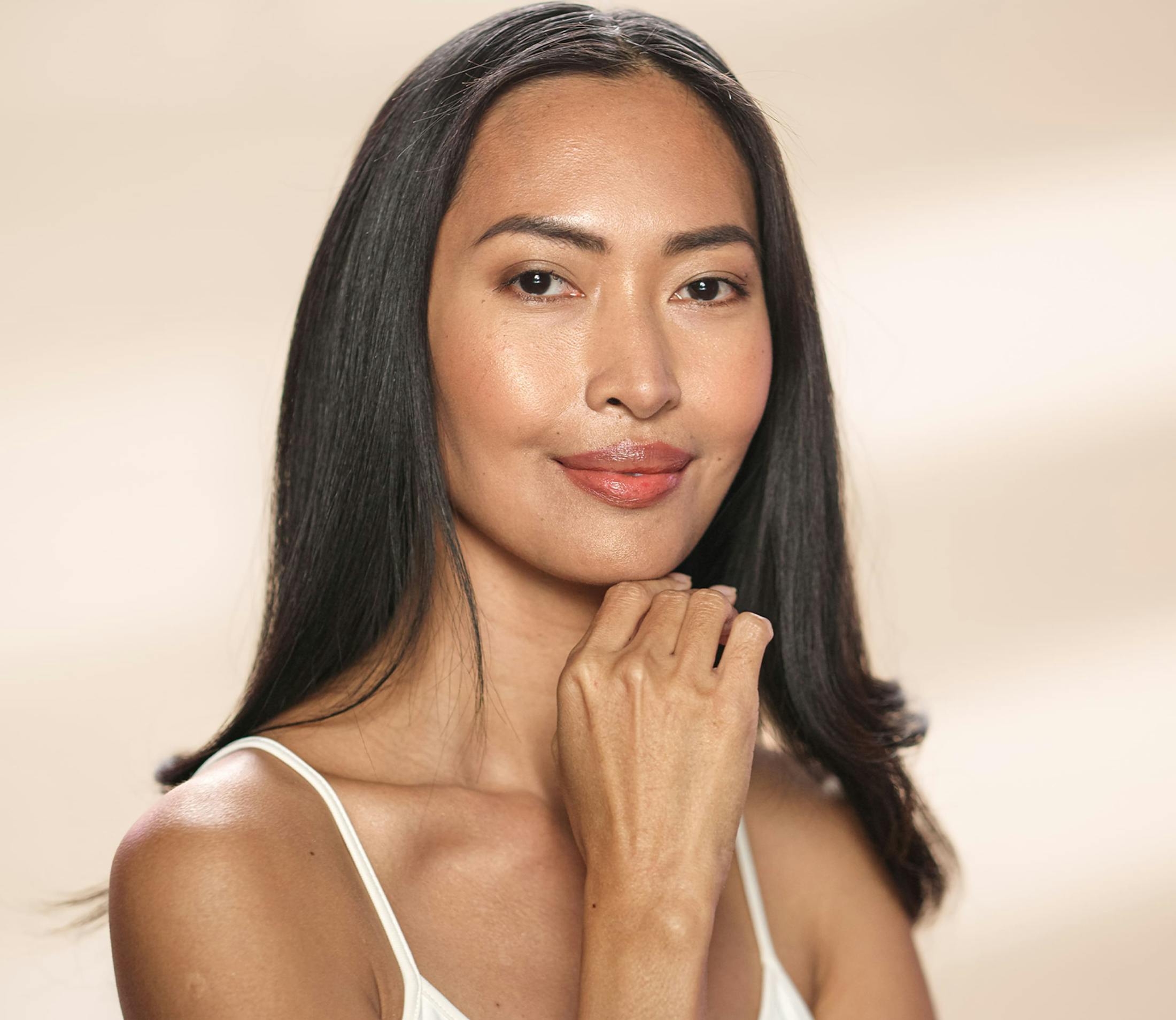 woman with white camisole and chin resting on her index finger