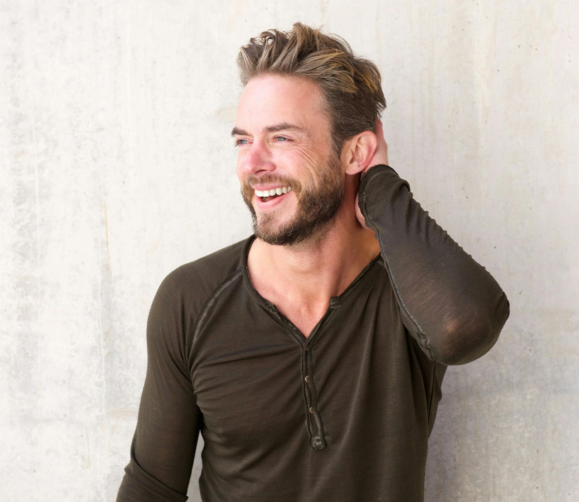 man in brown shirt placing his hand on the back of his head