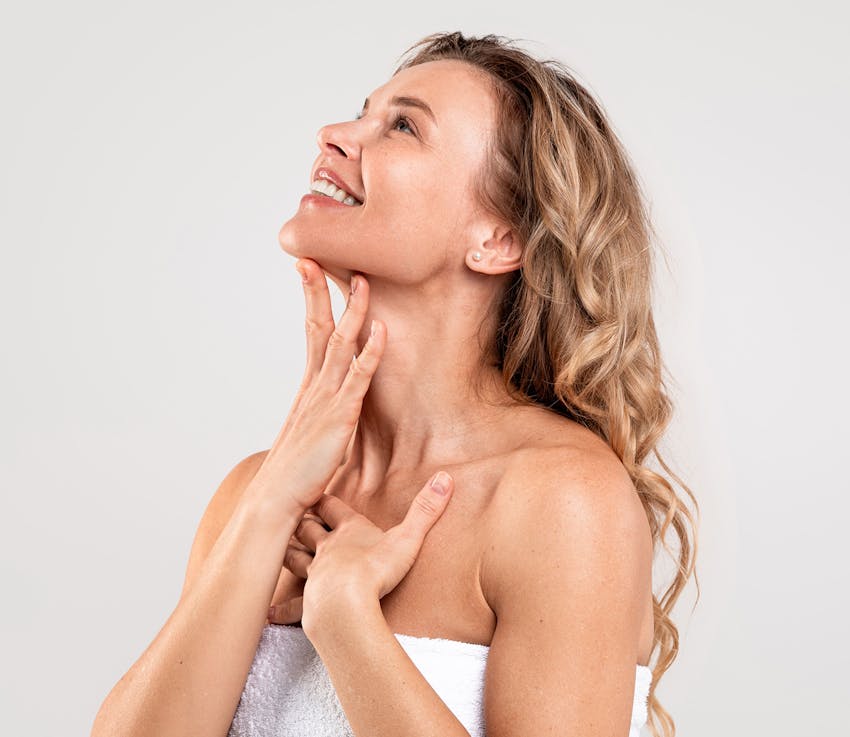 woman with hand on heck and chest smiling looking up