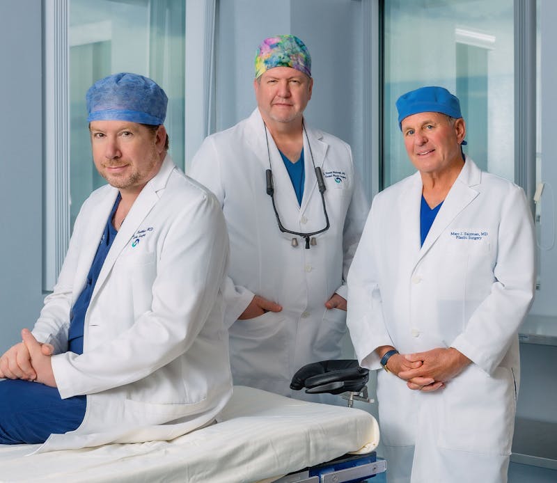 Dr. Kreithen, Dr. Holcomb, and Dr. Salzman standing in medical attire