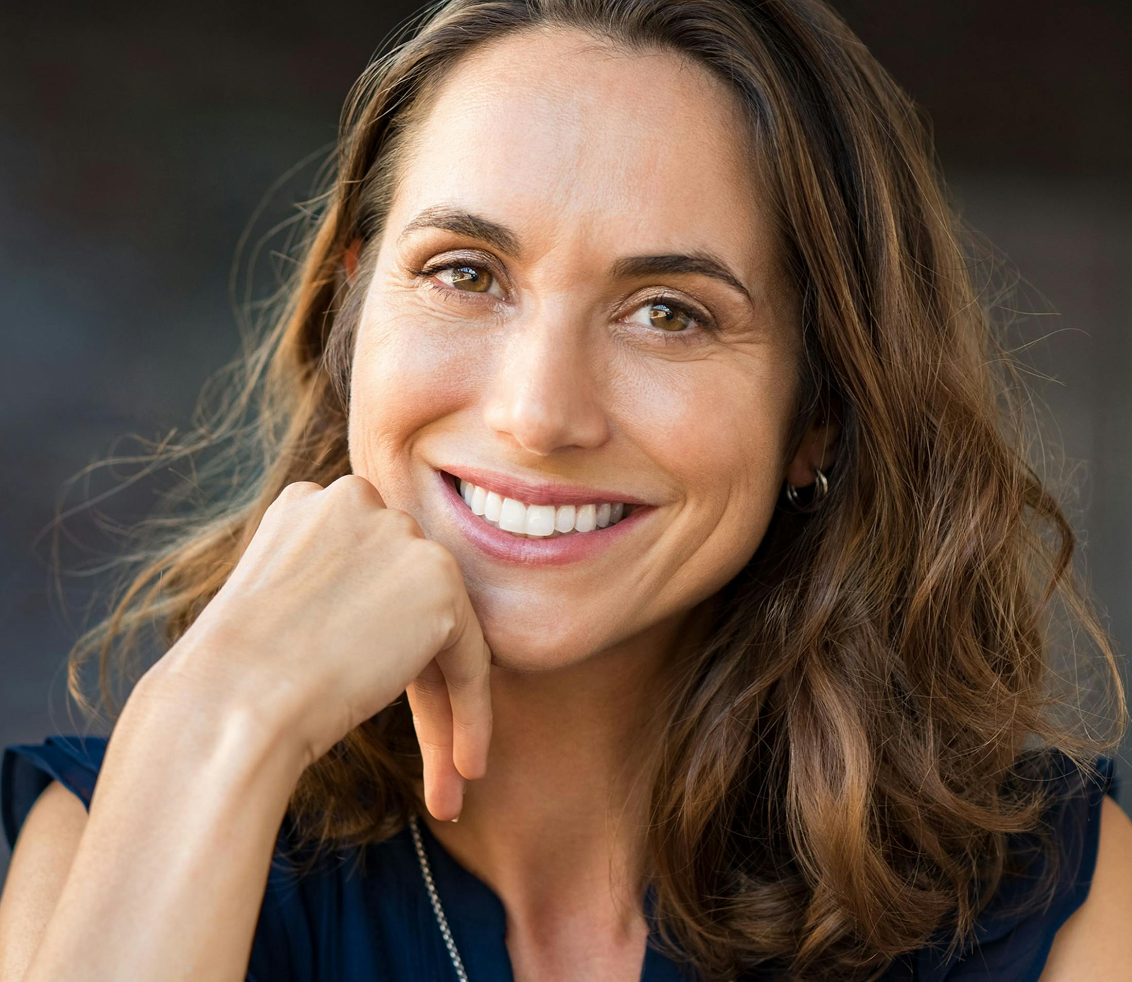 woman with short brown hair resting back of her hand on her chin