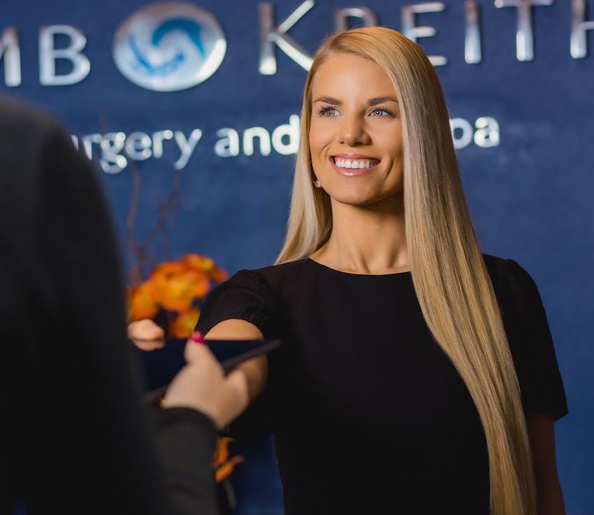 woman smiling and handing ipad to patient