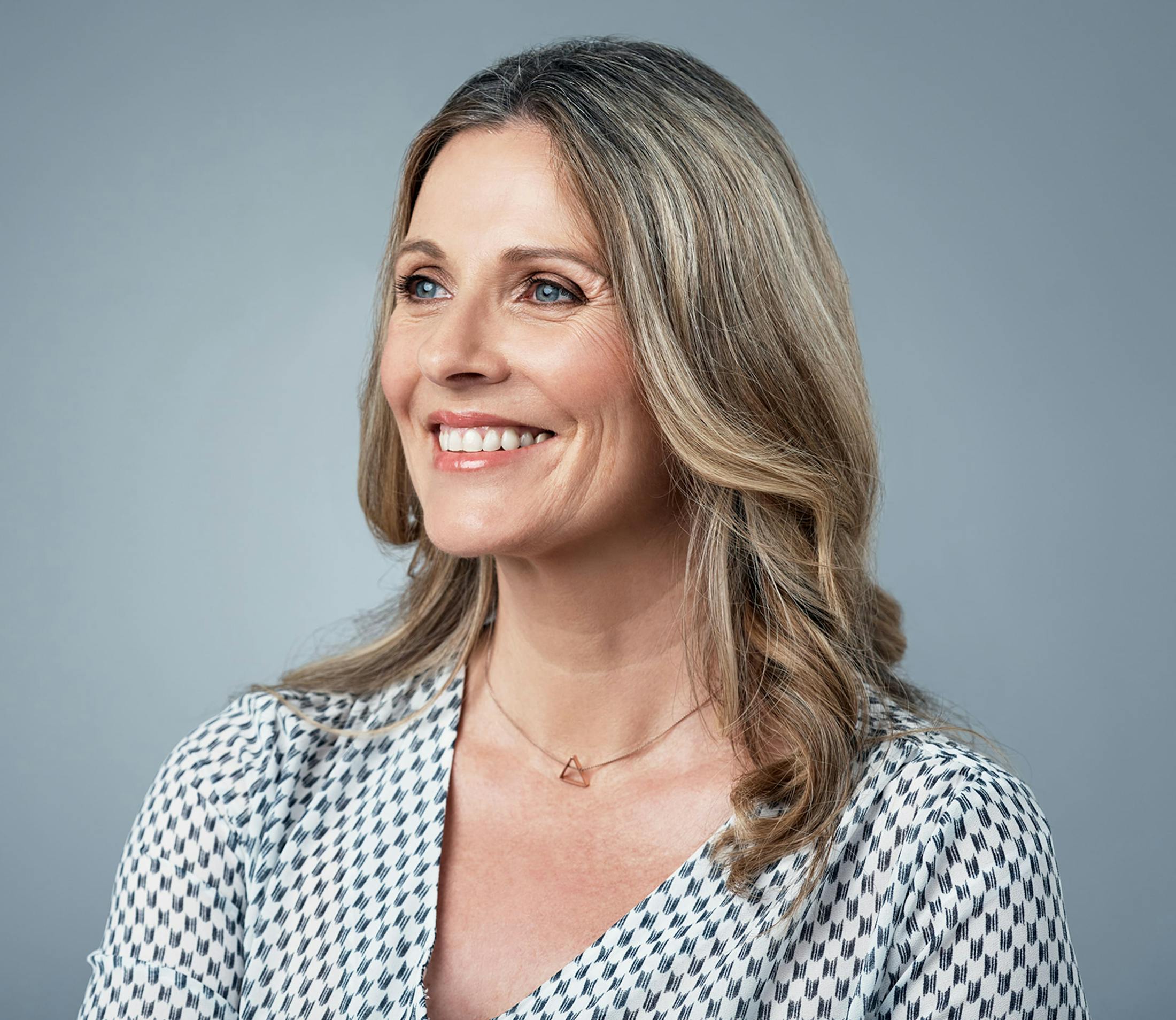 woman in white and black patterned shirt smiling