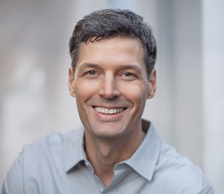 main in grey button up shirt smiling