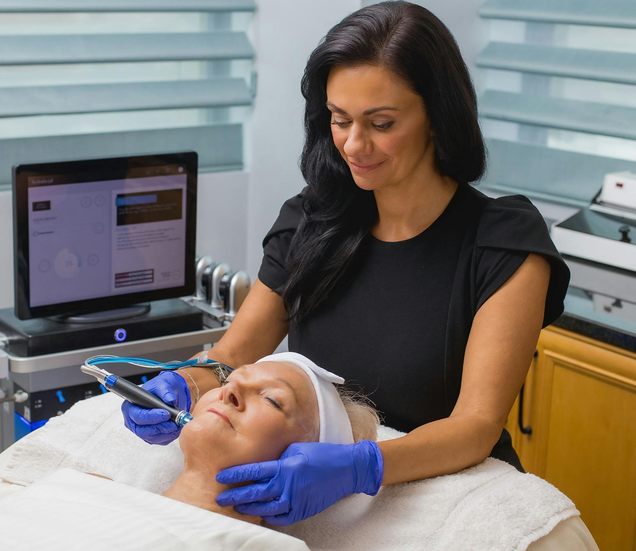 medical personnel using facial tool on patient laying down