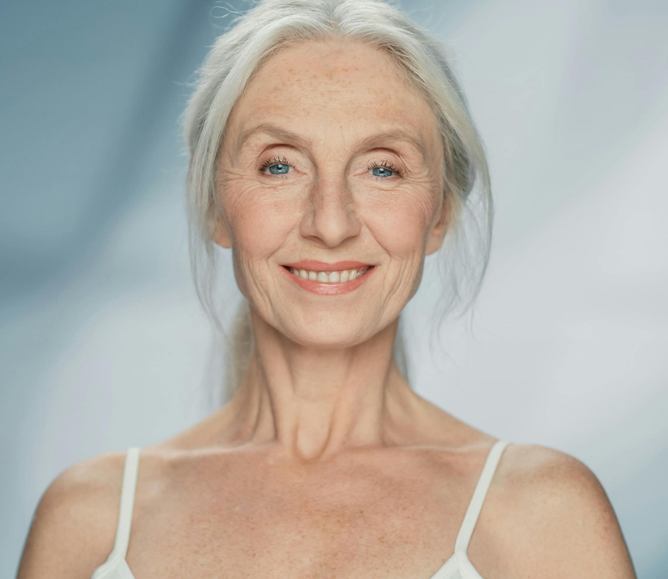 woman in white camisole looks forward with white hair in a ponytail