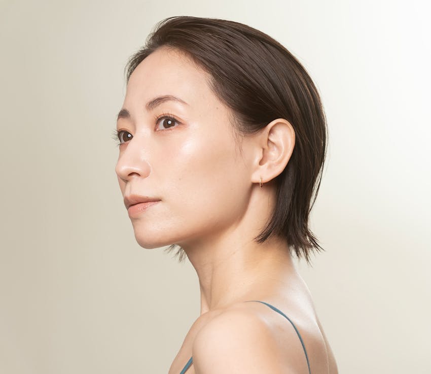 woman with hair brushed behind ears looking over her shoulder