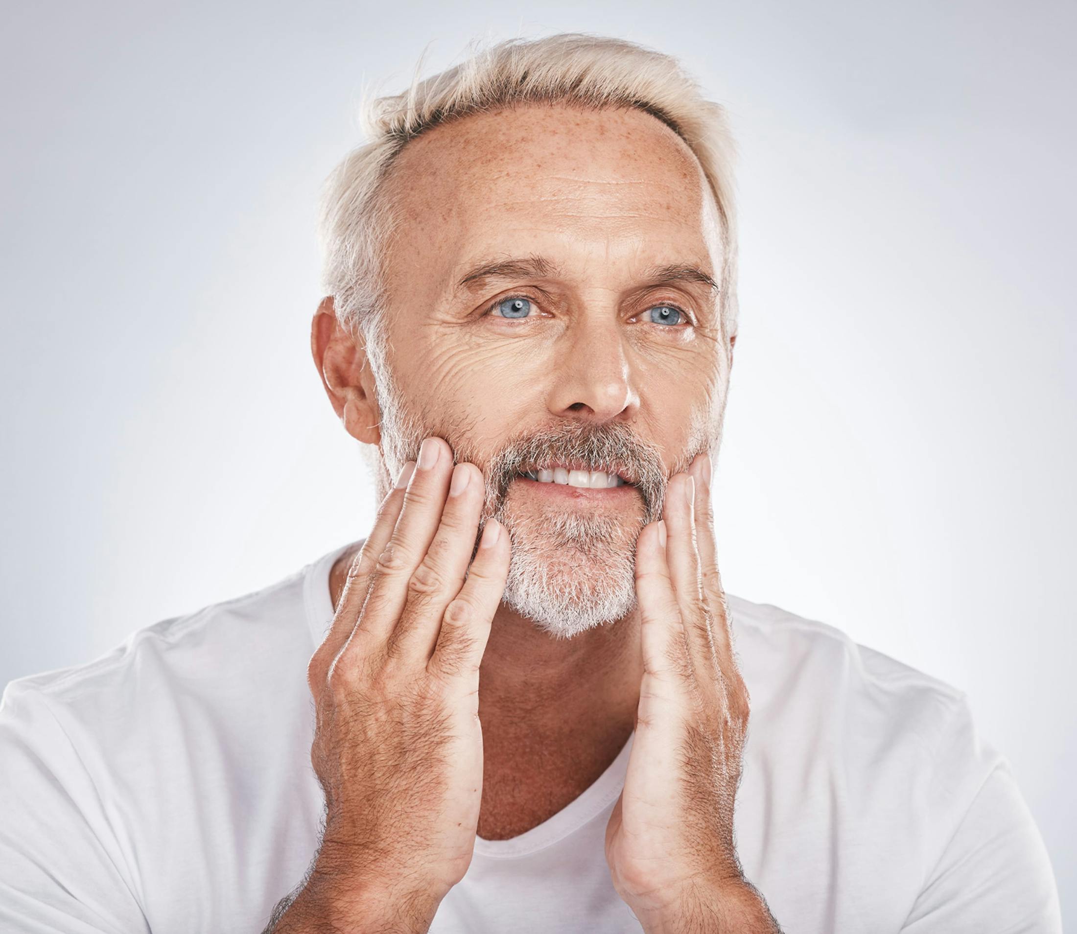 man smiling as he touches his chin