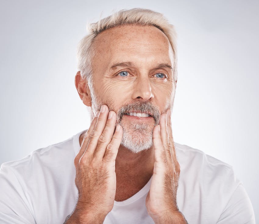 man smiling as he touches his chin