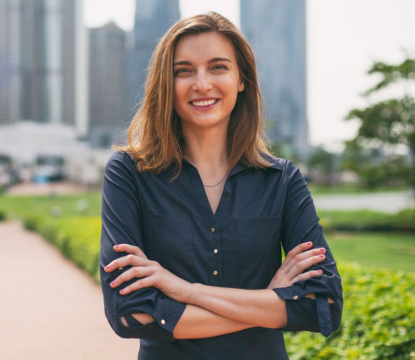woman outside smiling with her arms crossed