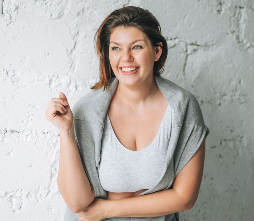 woman in grey shirt with grey jacket draped over her shoulders