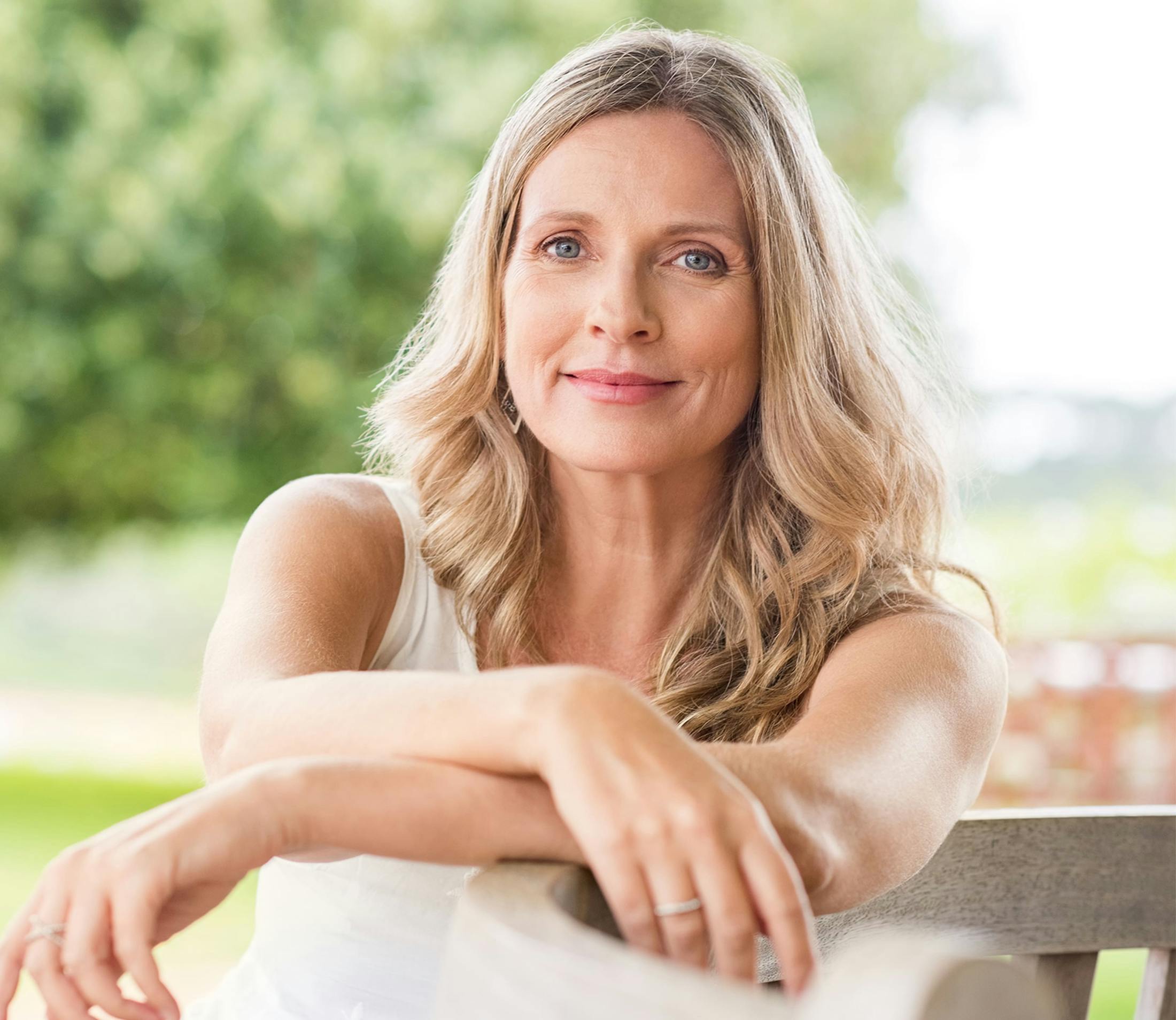 blonde woman grinning with arms crossed on railing