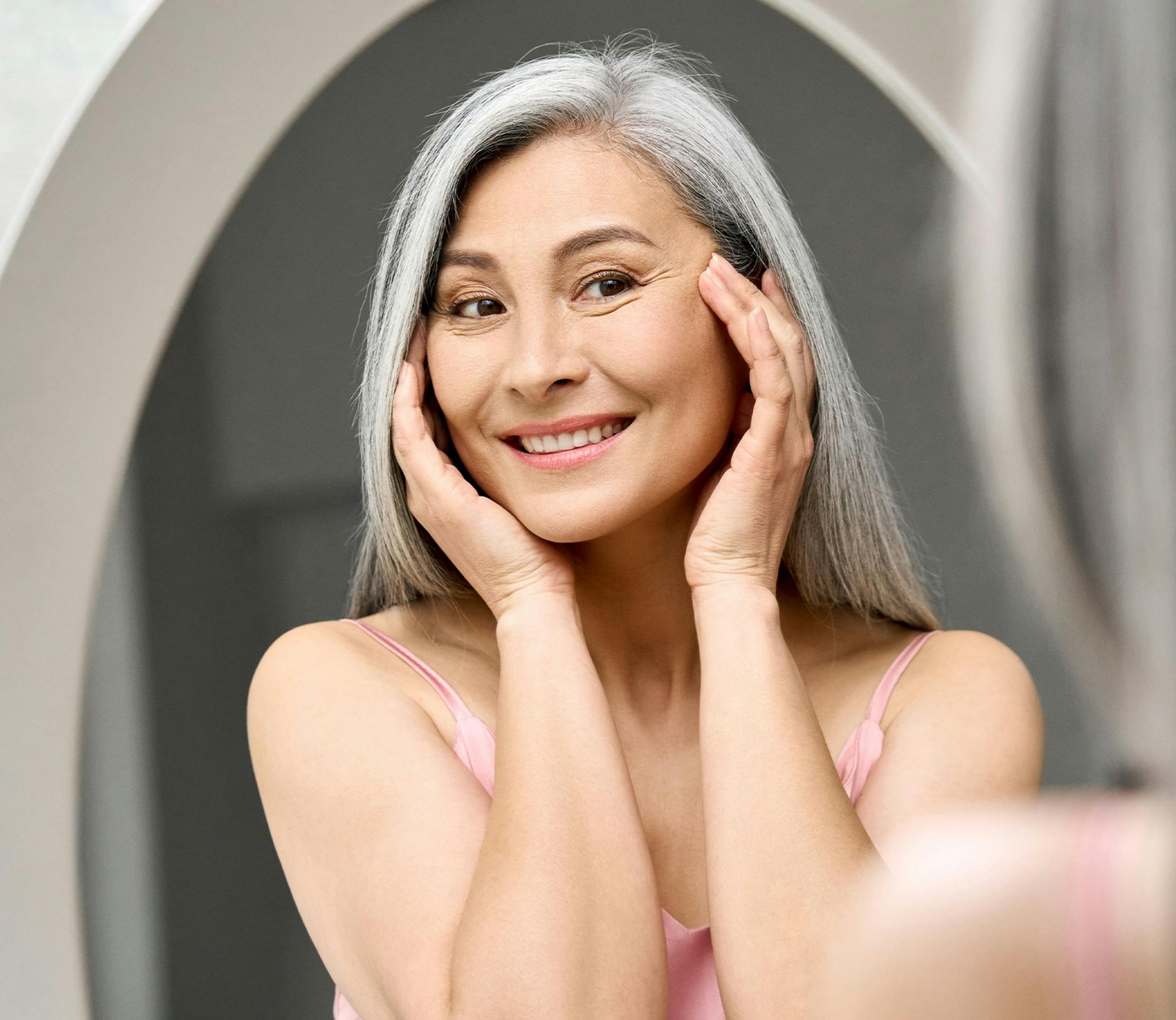 woman looking at herself in mirror touching her temples