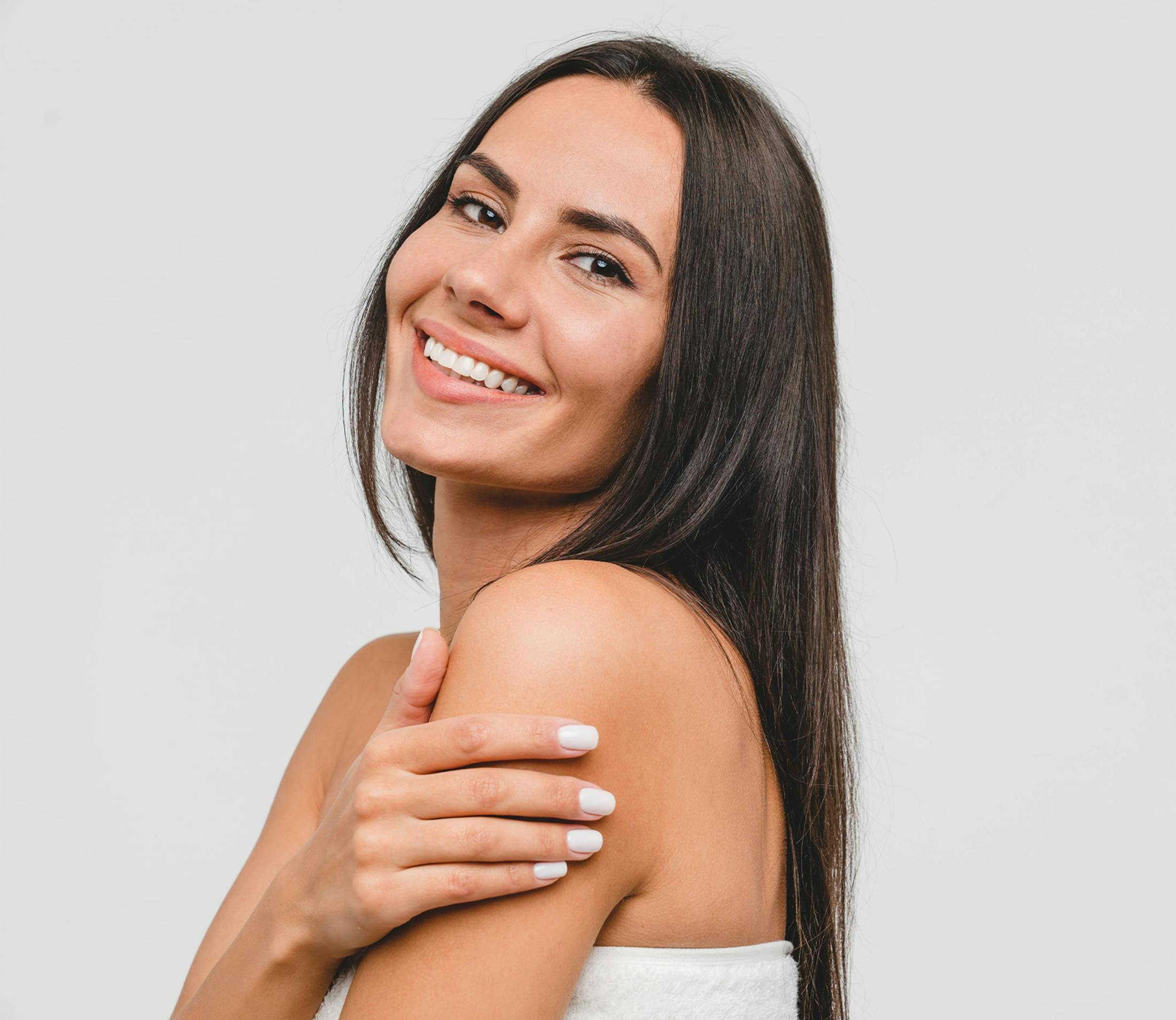 woman with straight brown hair smiling with her hand on her arm