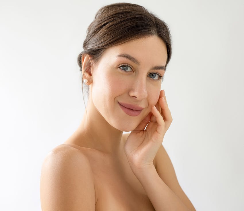 brunette with hair in bun touching her chin