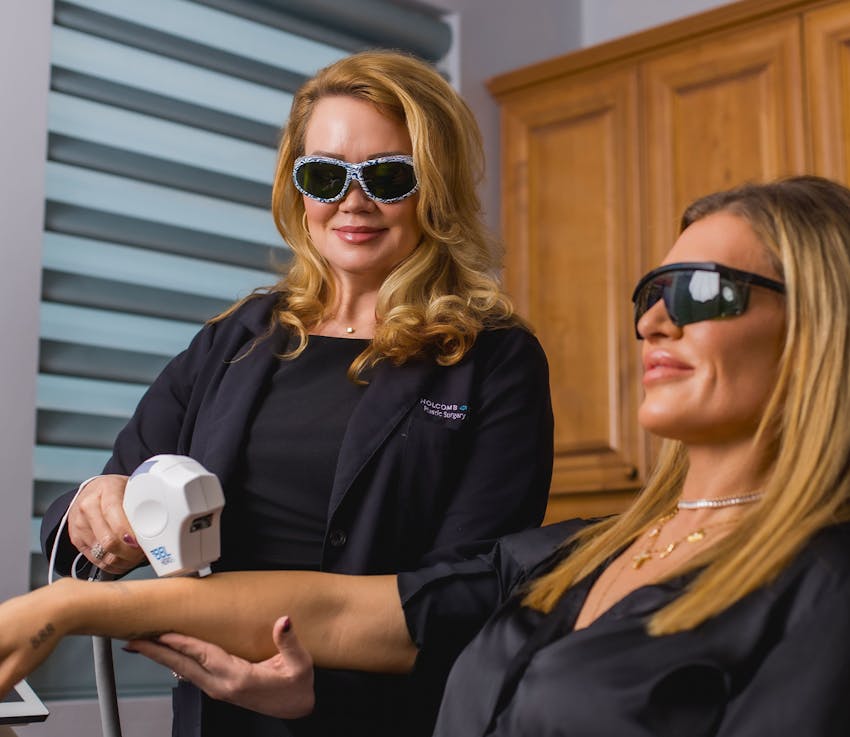 woman using BBL photorejuvenation tool on patients arm while they both wear protective eyewear