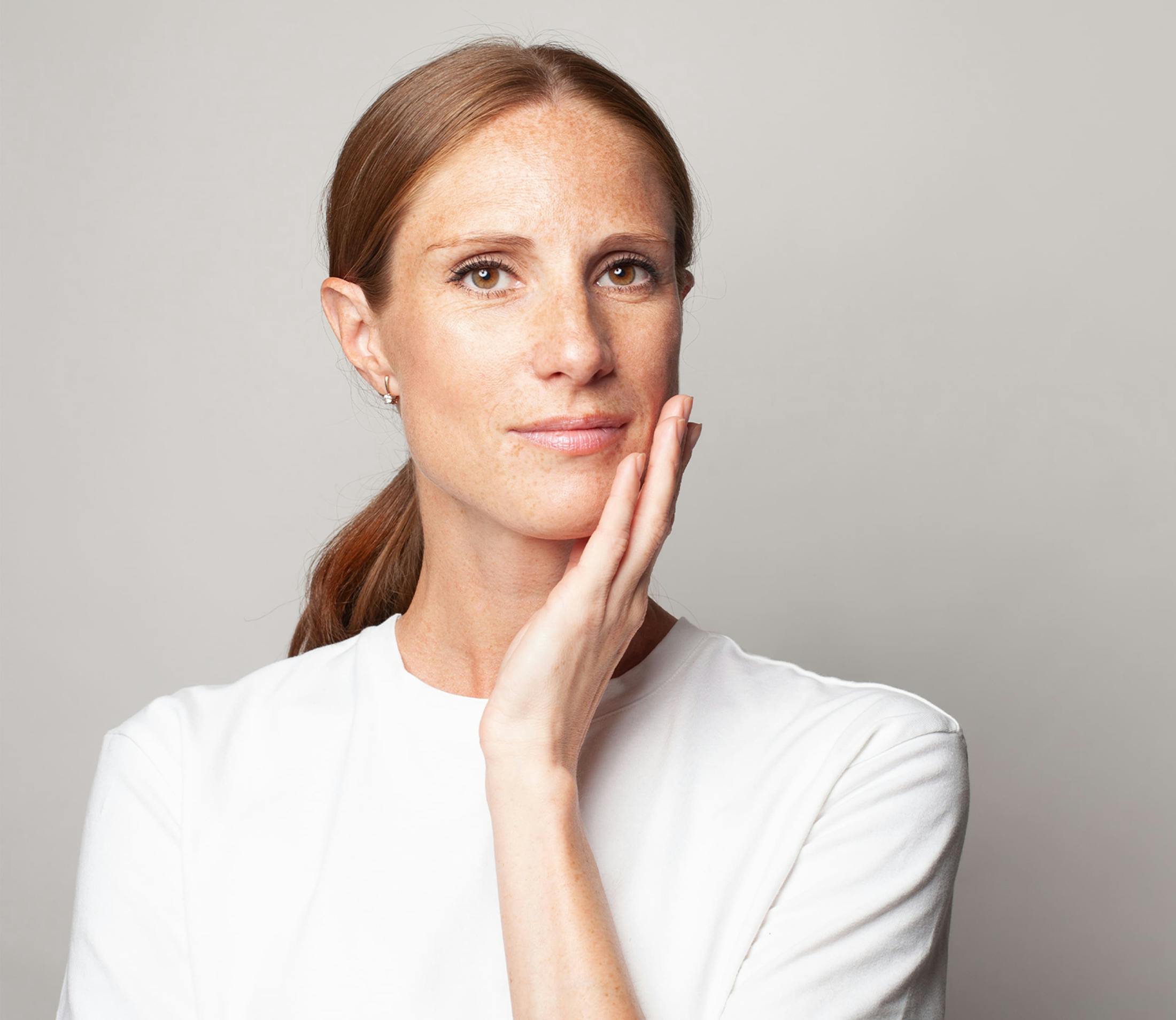 woman in white shirt touching her chin