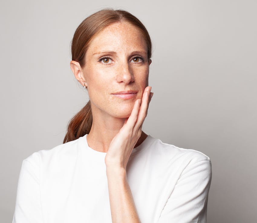 woman in white shirt touching her chin