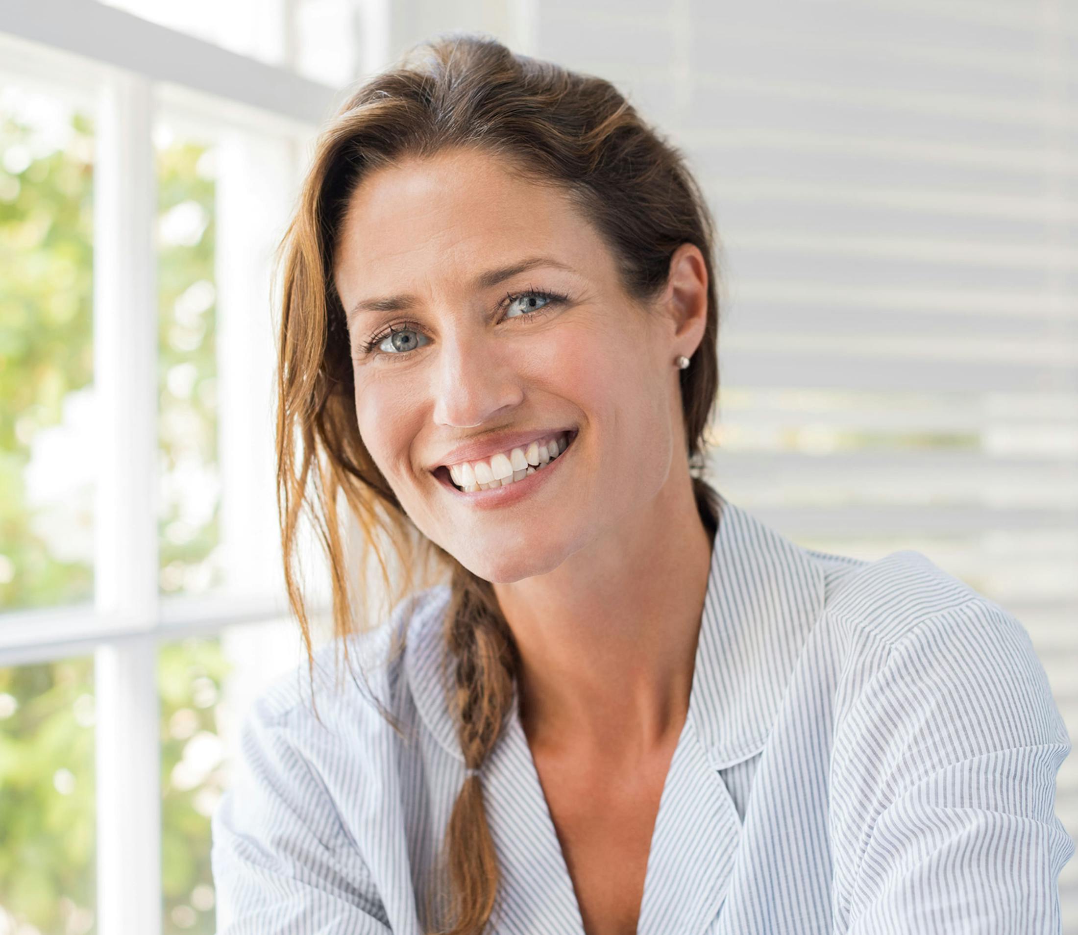 woman in white striped shirt smiles with hair in a braid
