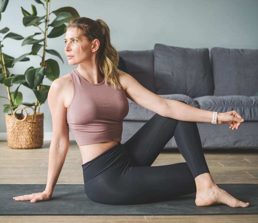 woman on yoga mat in athletic clothes is stretching