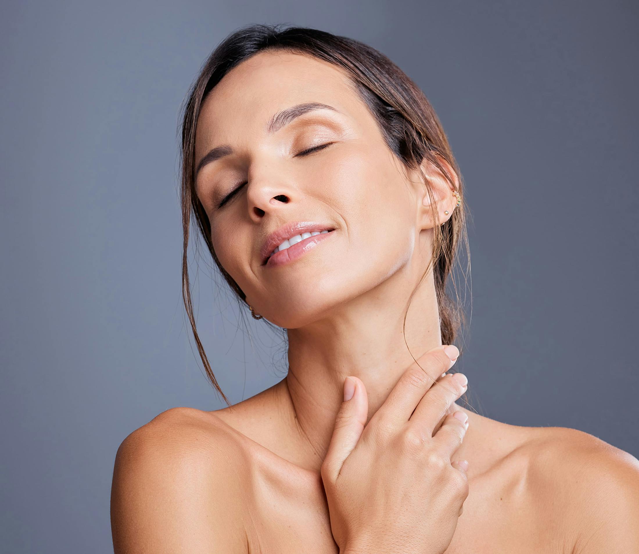 woman with her head leaned back and eyes closed as she touches her neck