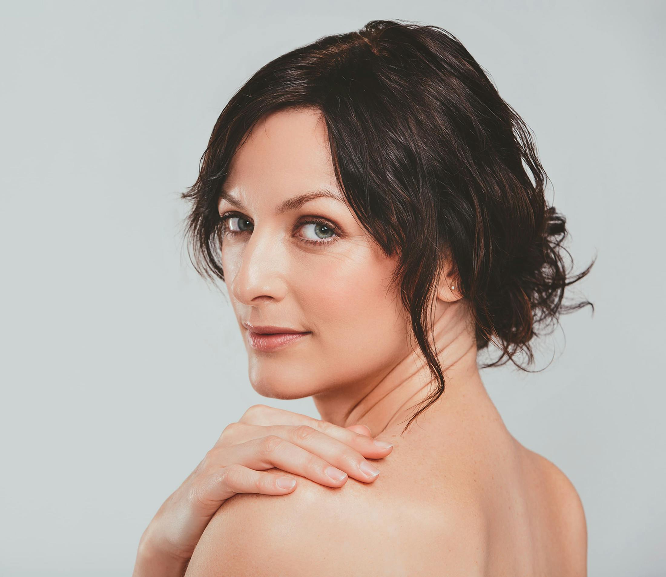 woman with hand on shoulder, looking over her shoulder