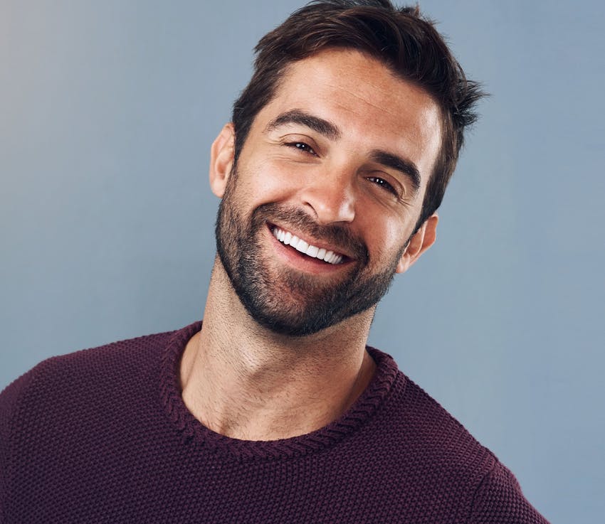 man in maroon sweater smiling with his head tilted