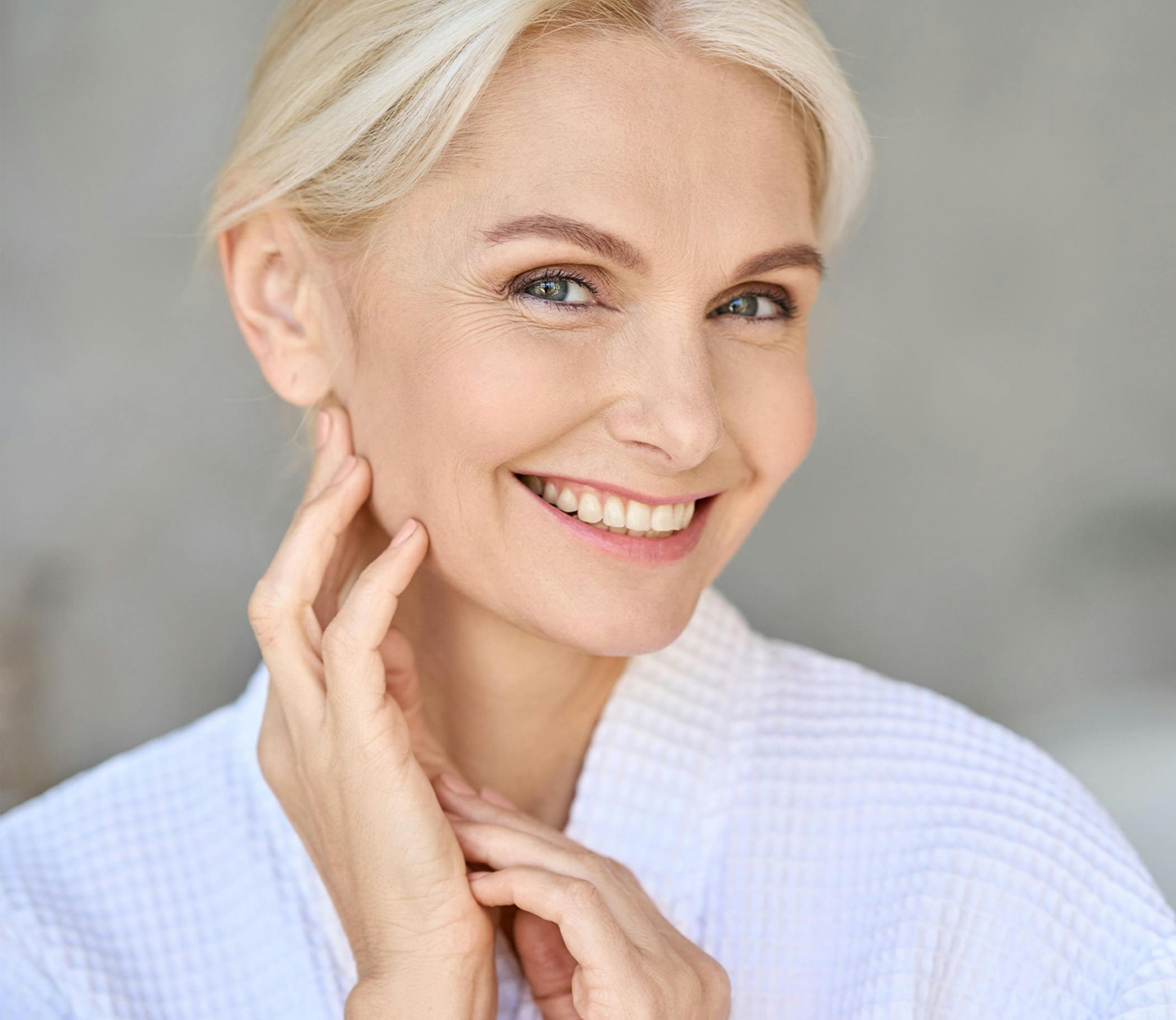 woman with short blonde hair smiling with her hand near her ear