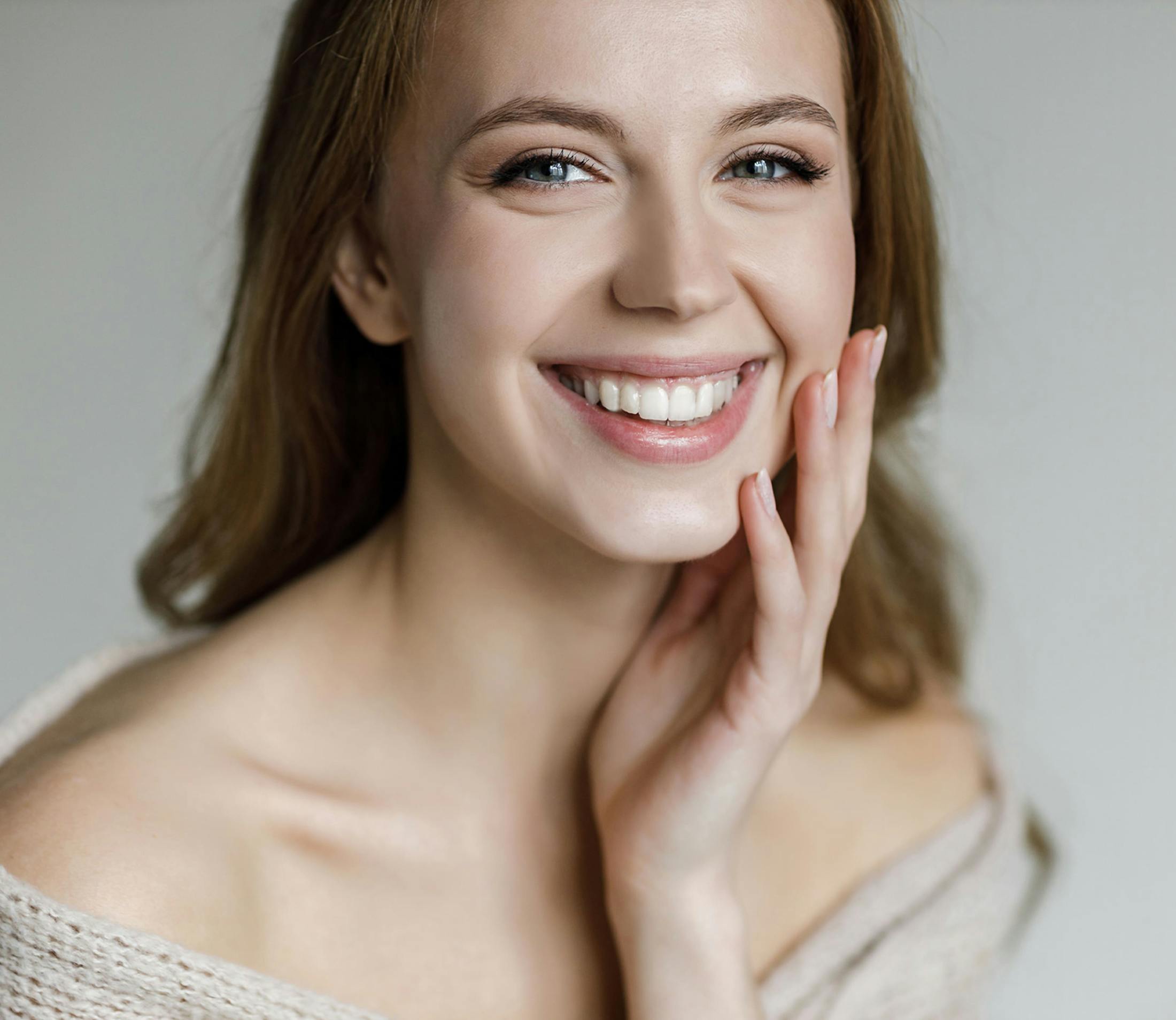 woman smiles looking forward hand cupping her chin