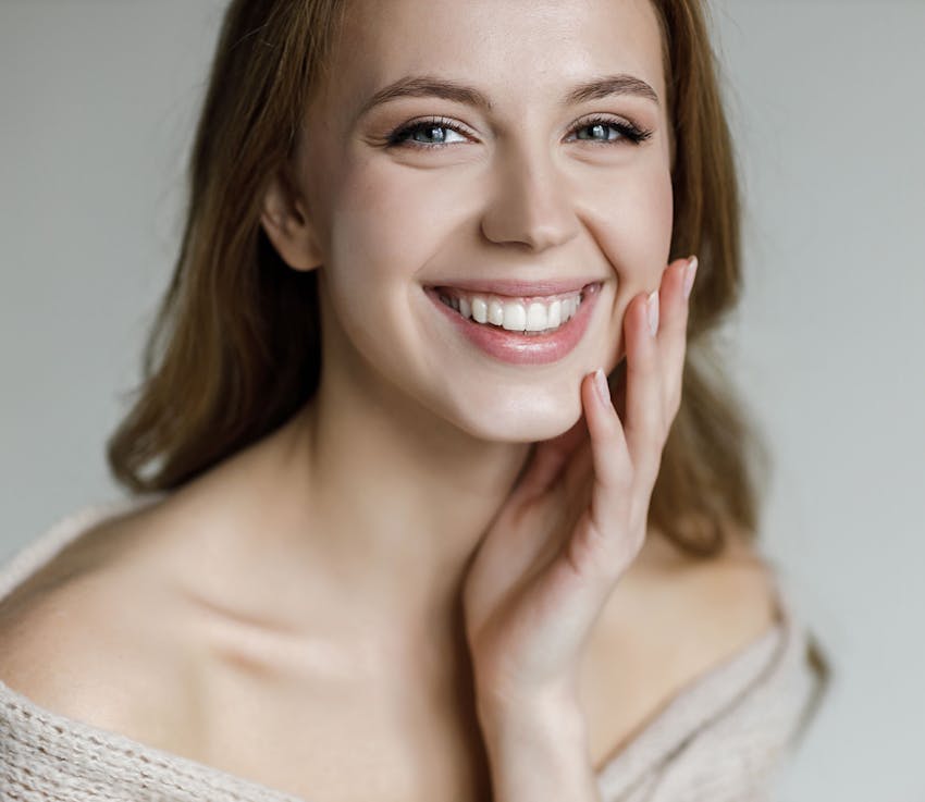 woman smiles looking forward hand cupping her chin