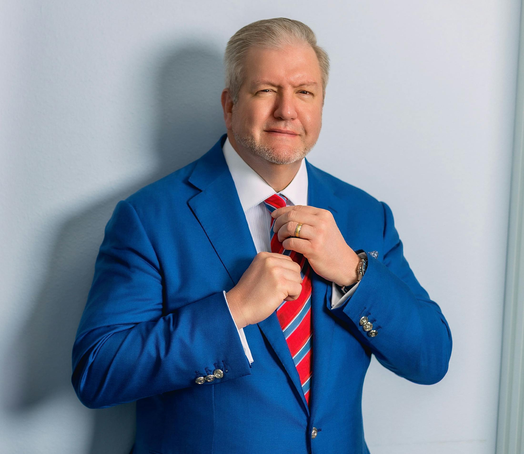 Dr. Holcomb in blue suit fixing his tie