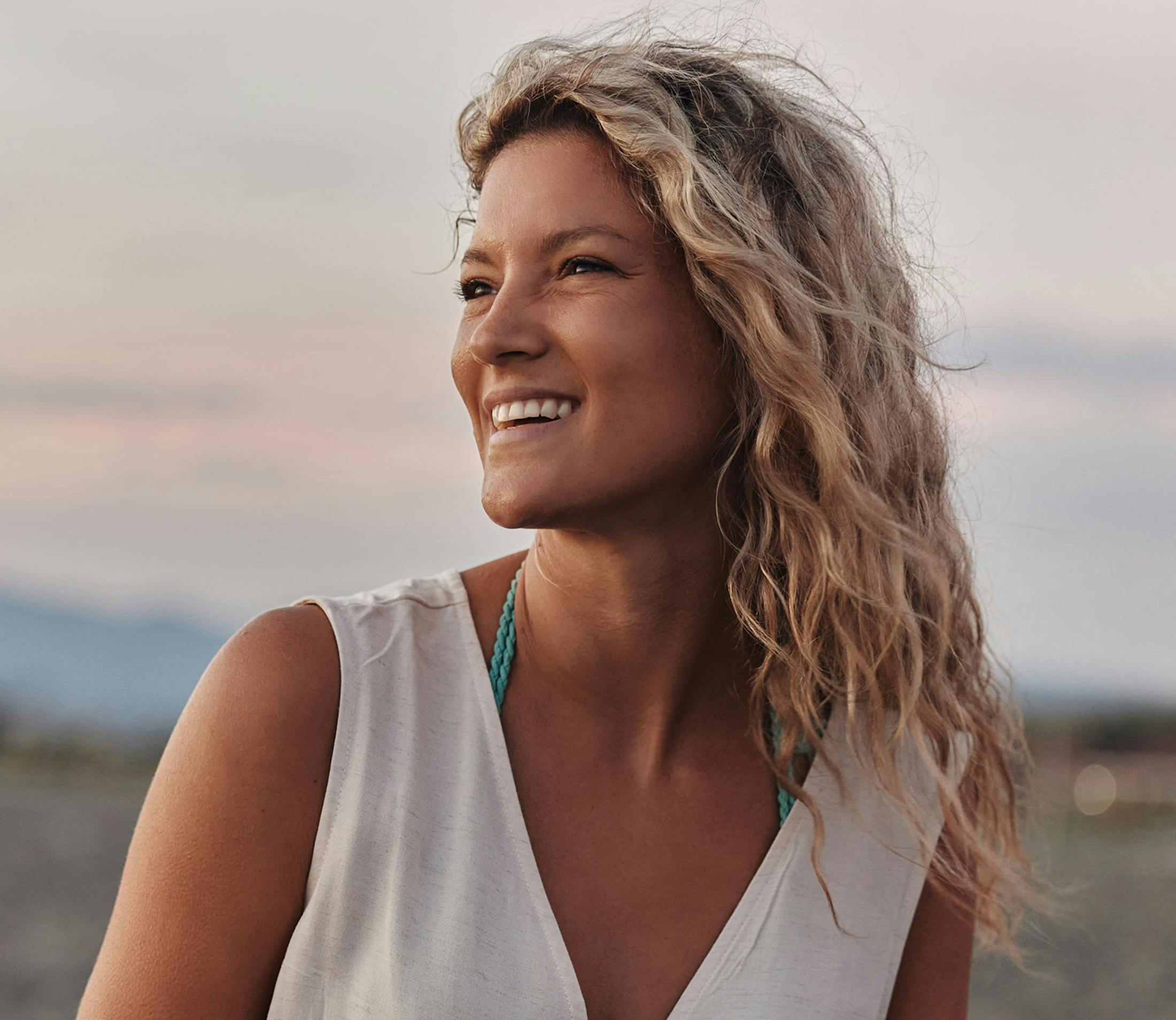 woman in white v-neck tank with blonde wavy hair