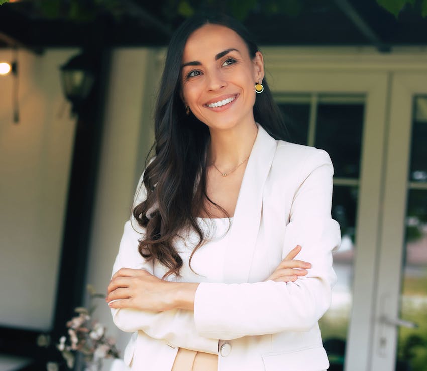 woman smiling outside with her arms crossed