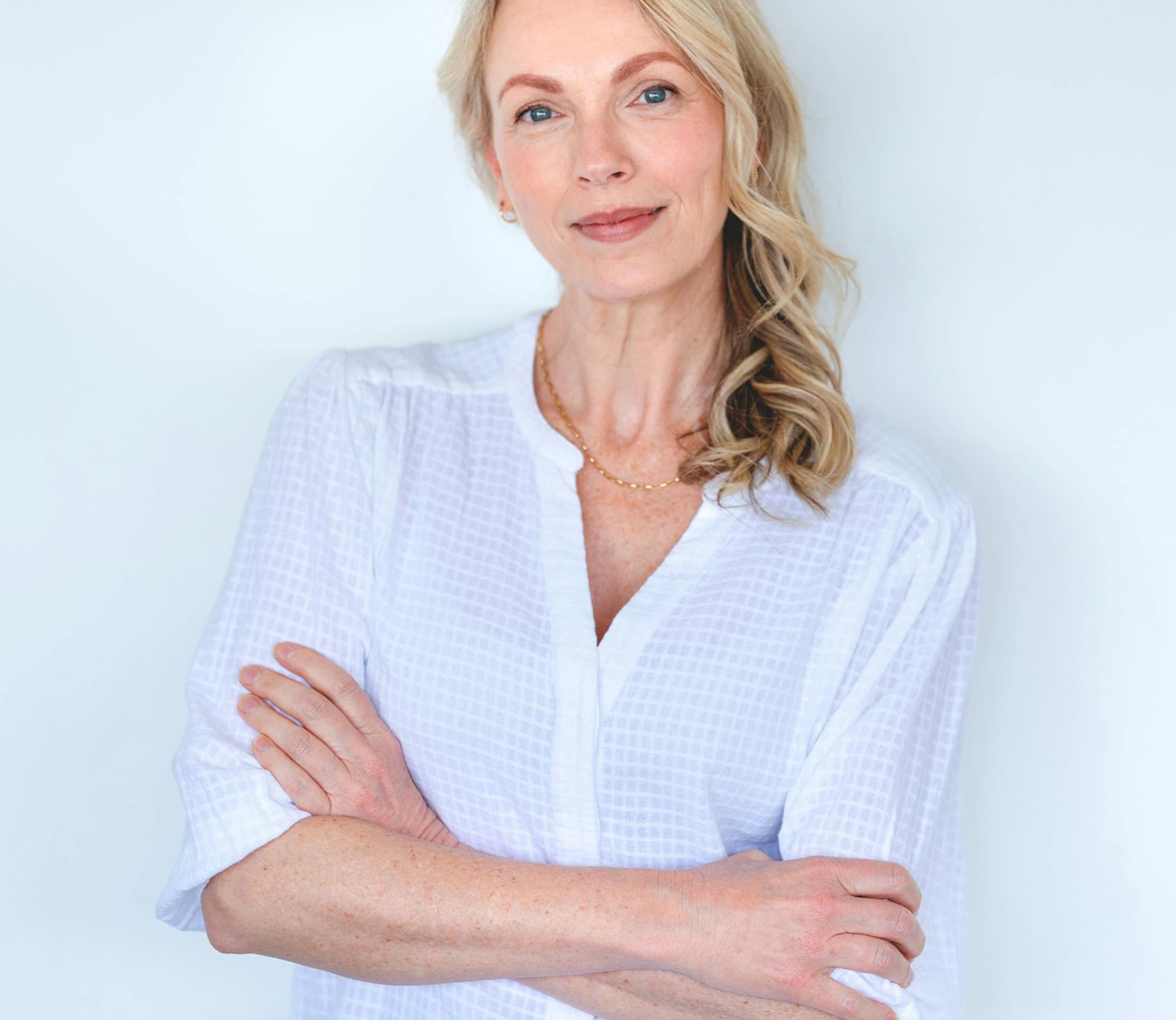 woman in white shirt looking forward with her arms crossed in front of her