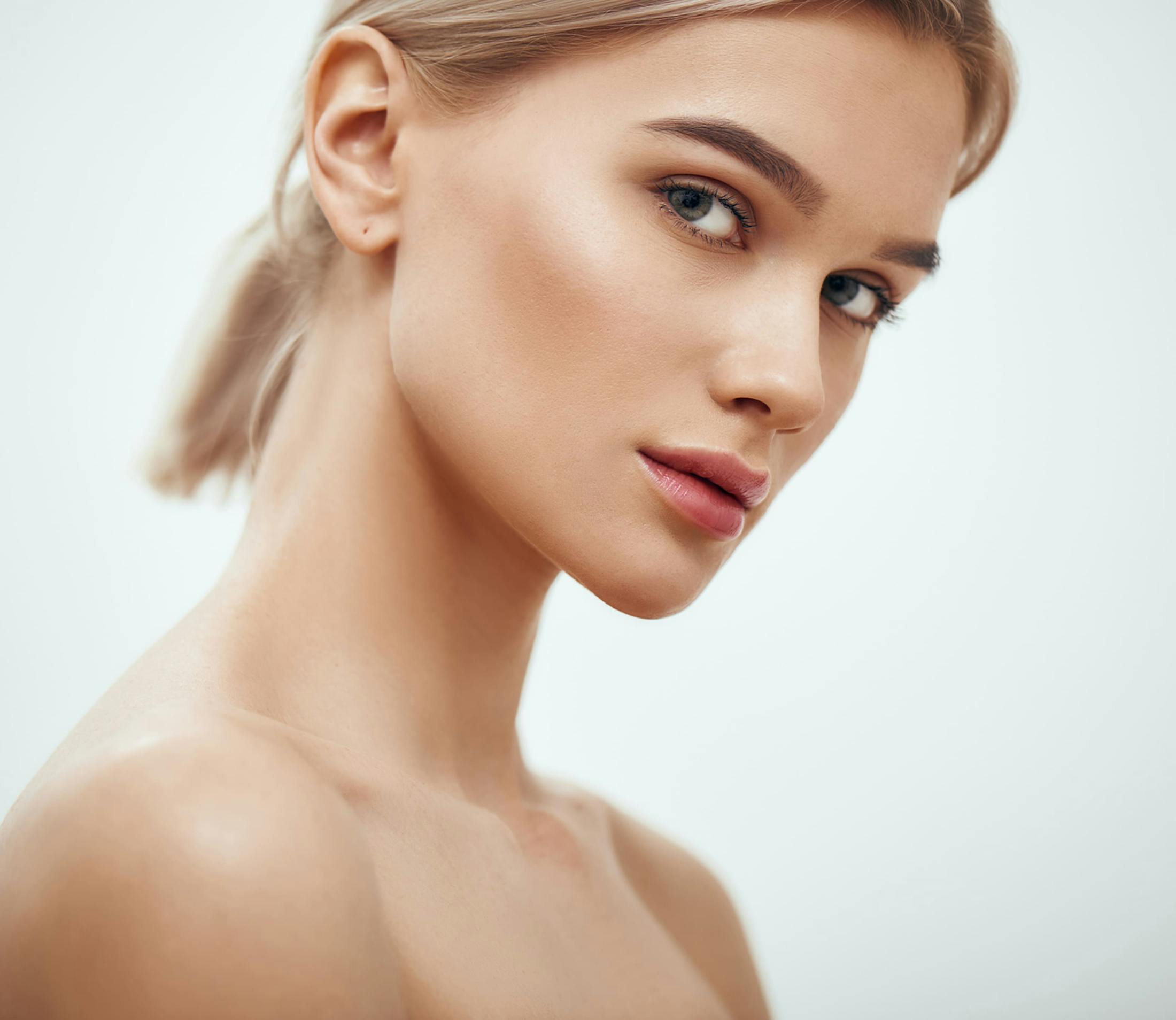 woman looking over her shoulder with short blonde hair tied in ponytail