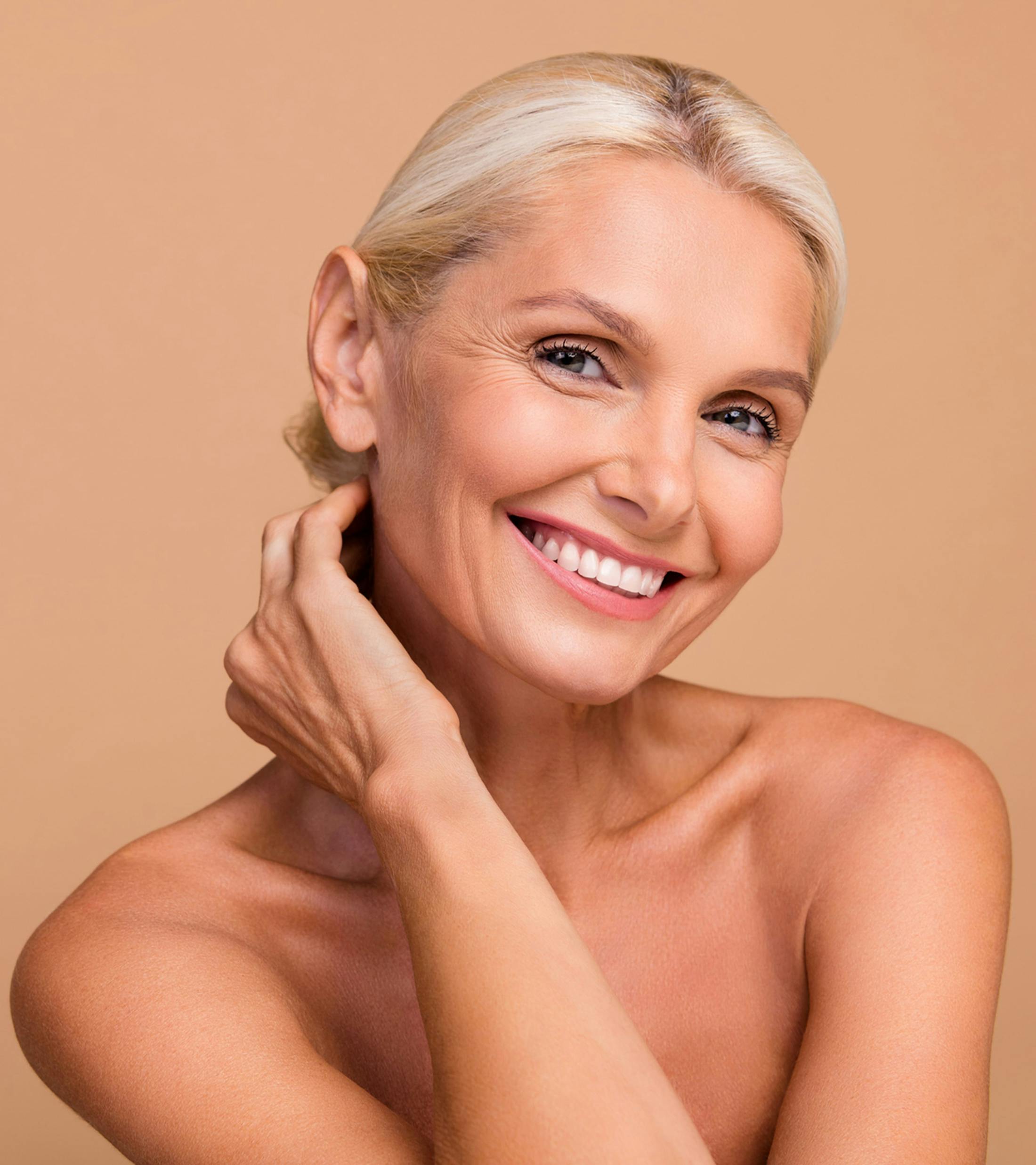 woman with hair in bun touches the back of her neck smiling