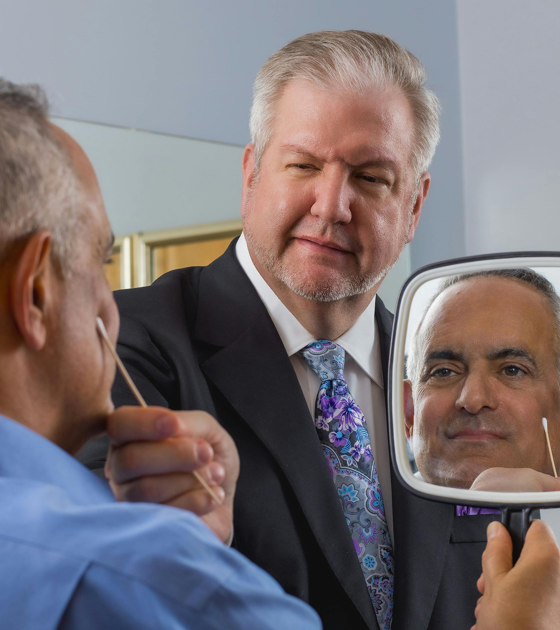 doctor showing male patient his cheek in the mirror