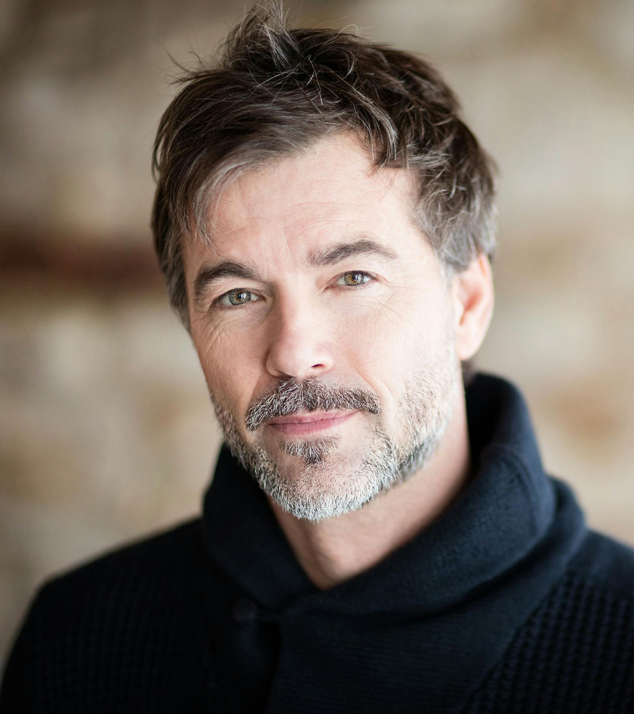 man with dark hair and grey beard in black sweater