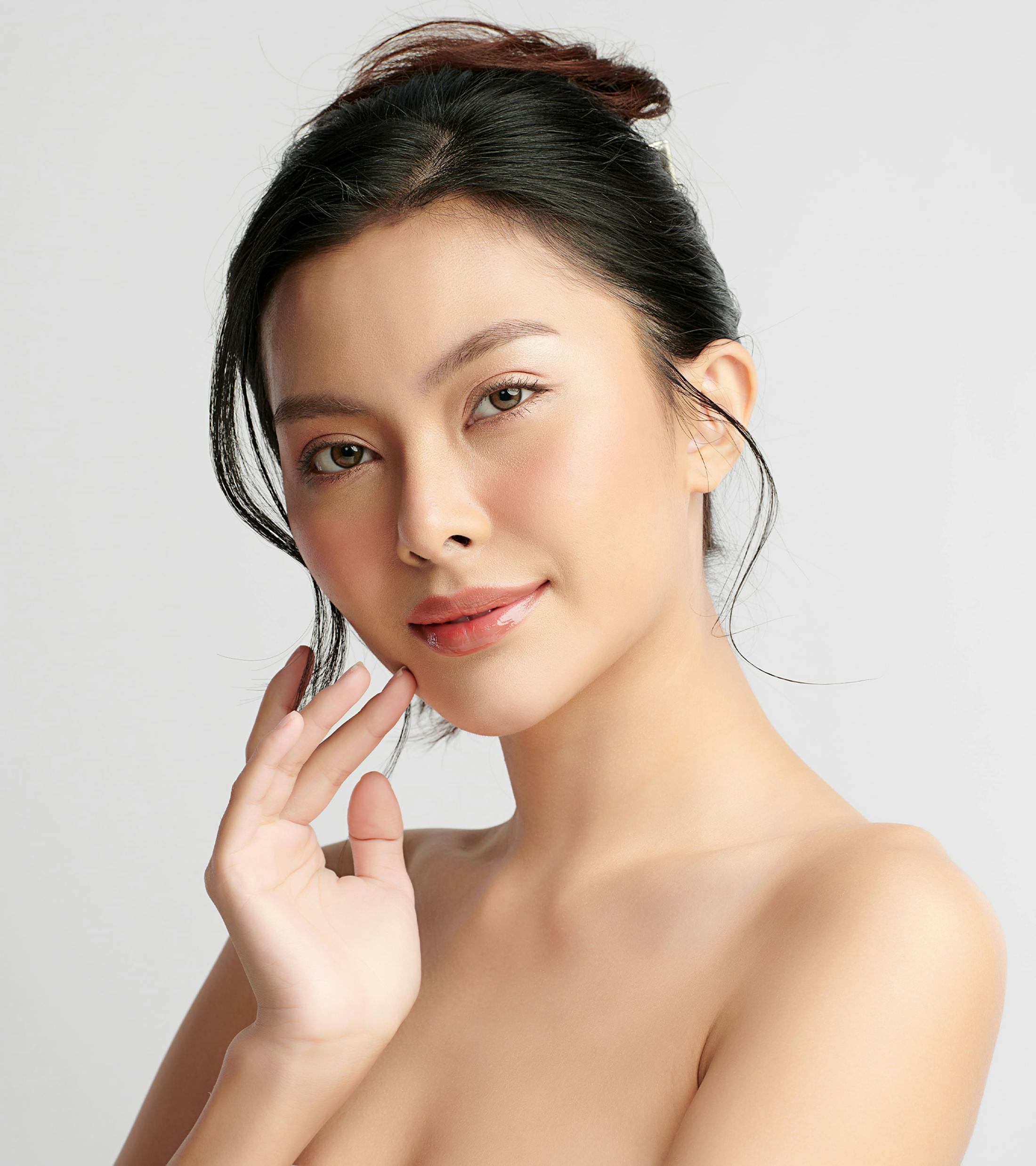 coman touches her chin with hand while hair is in bun