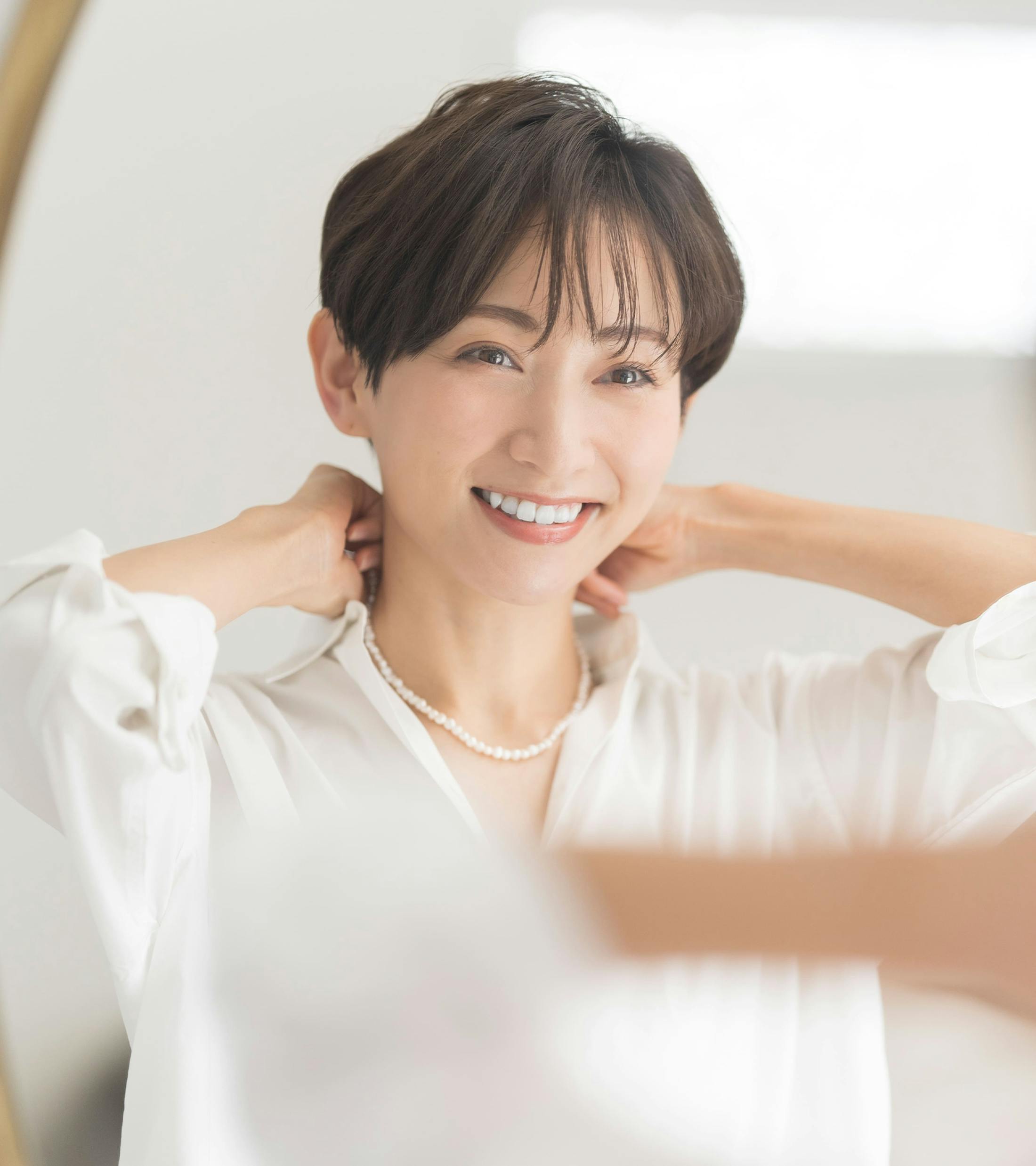 asian woman with short hair smiling and looking in mirror