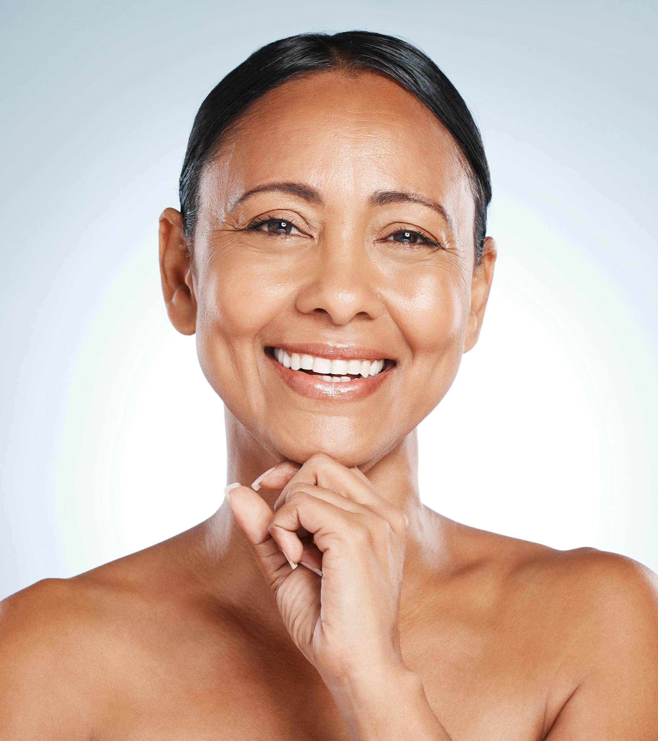 woman smiles while placing her fist under her chin