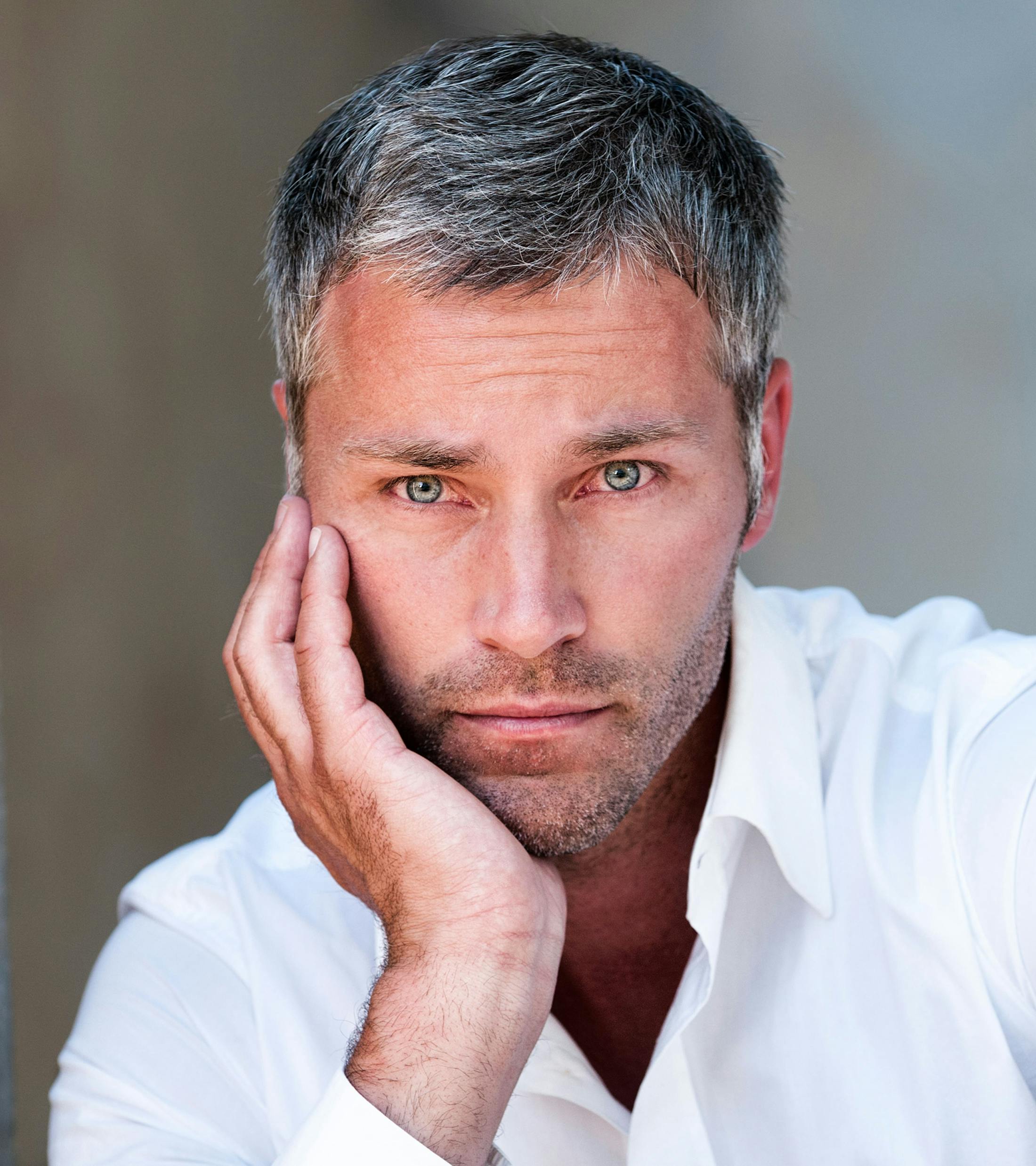 man with gray hair and hand pressed to his chin
