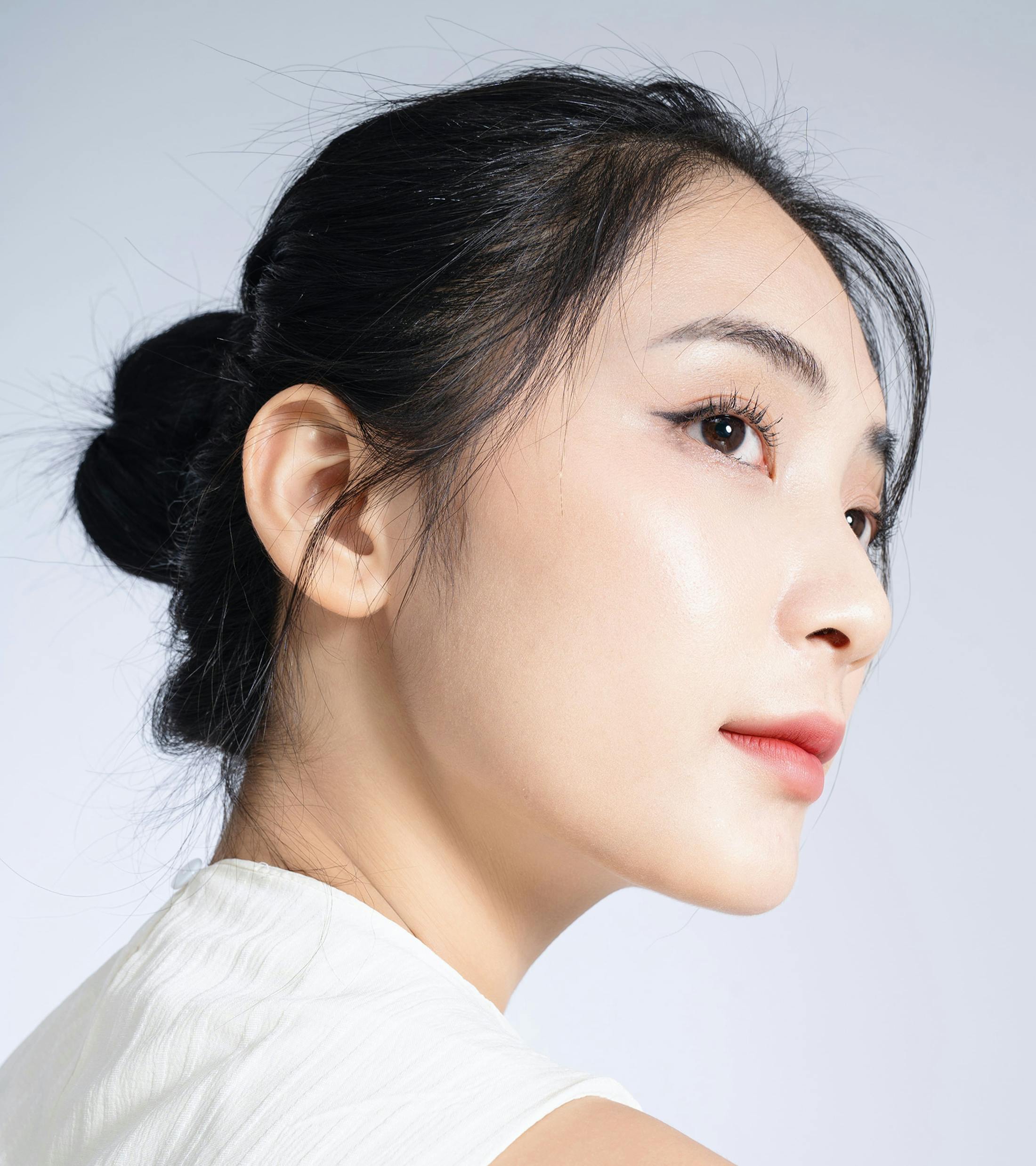 woman looks to the side with dark hair in bun