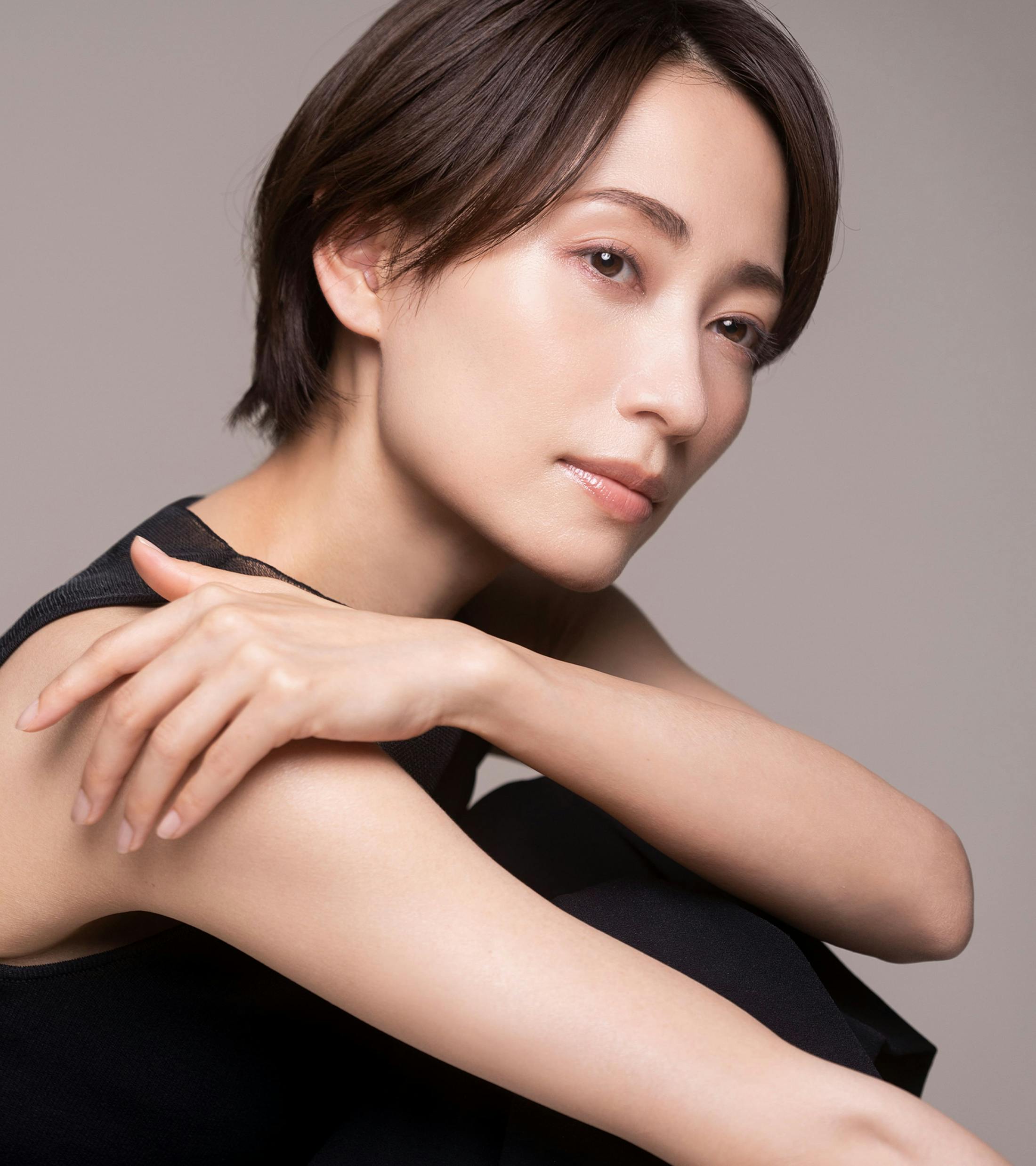 woman holds her shoulder while looking forward wearing all black