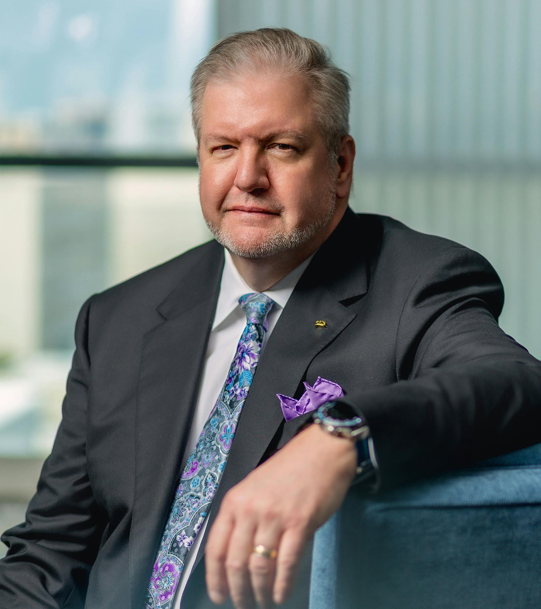 Dr. Holcomb seat on a blue chair with his arm resting on the chair arm