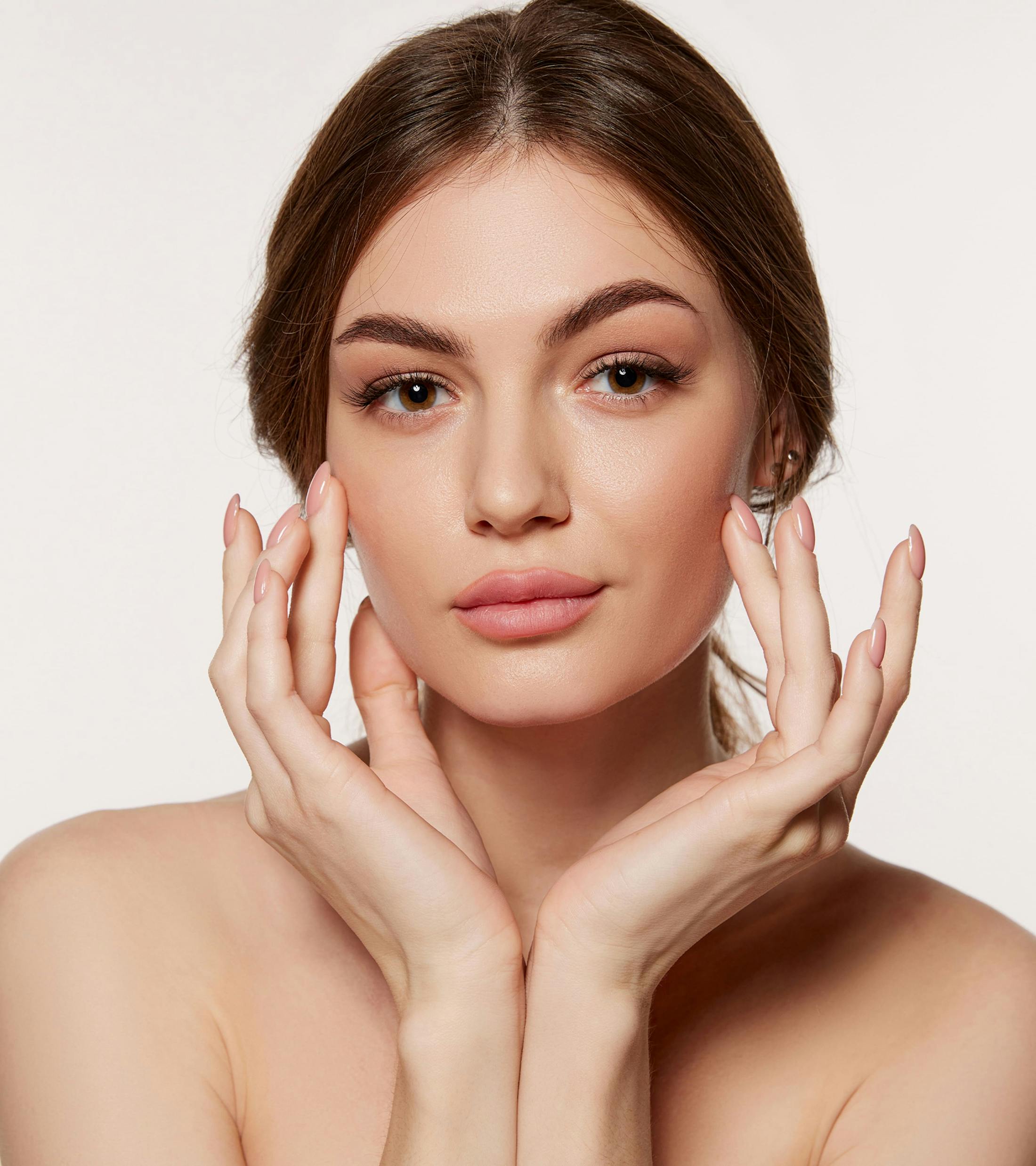 woman looking forward with both hands touching her cheek bones