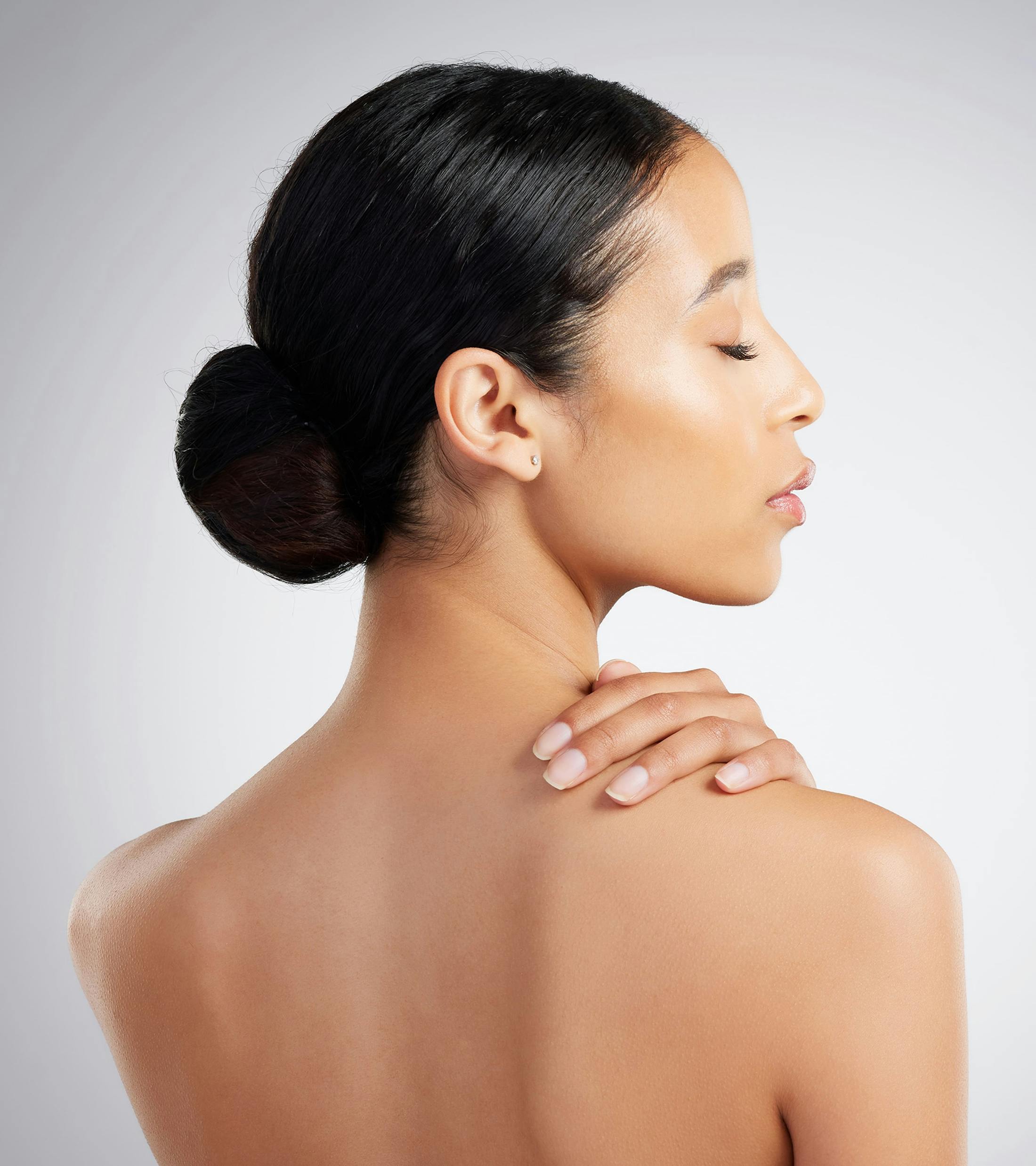 woman's backside with her hand on her shoulder and her hair in a bun