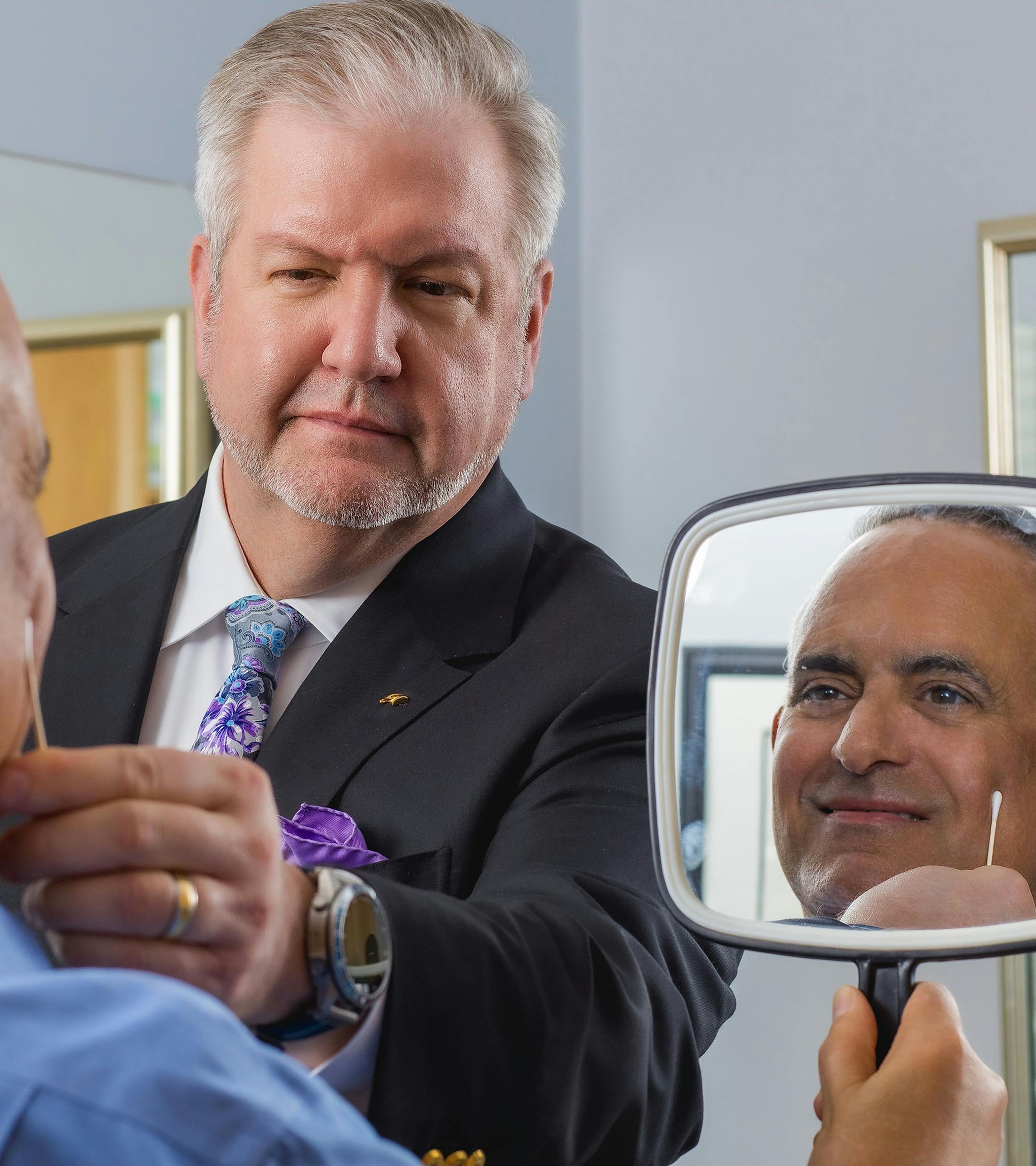 Dr. Holcomb in exam with patient while patient holds mirror looking at himself