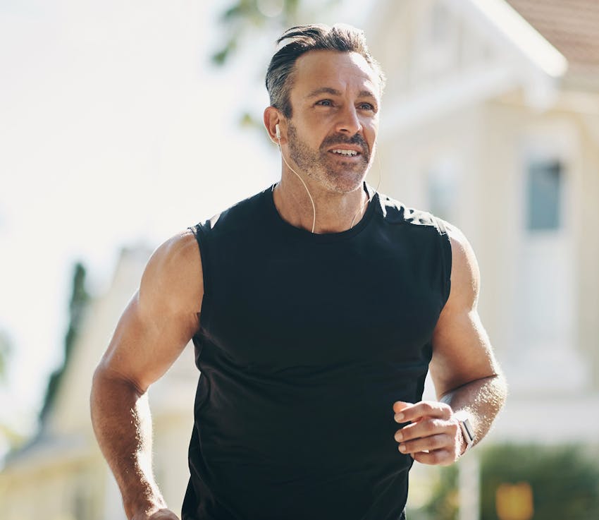 man running in black tank with earbud in his ear