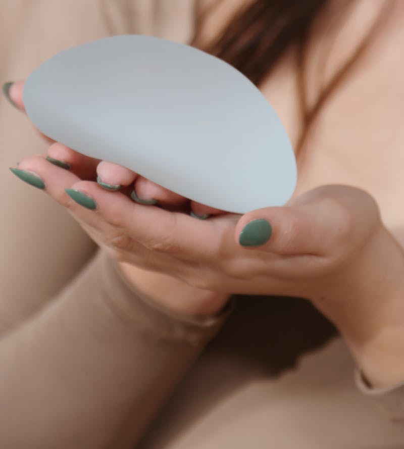 woman holding an example of a breast implant